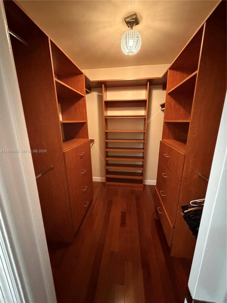 2215 NE 204th Street, Miami, Miami, FL 33180 Hardwood flooring complemented by built-in wood-finish cabinetry, integrated shelving, and a decorative ceiling fixture