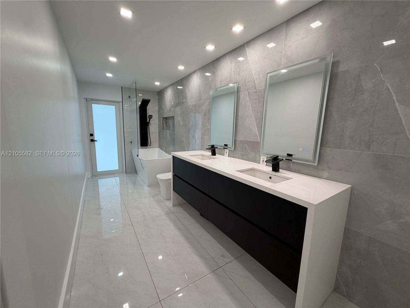 2215 NE 204th Street, Miami, Miami, FL 33180 Dual vanity with waterfall countertop, matte black fixtures, integrated sinks, and mirrored medicine cabinets