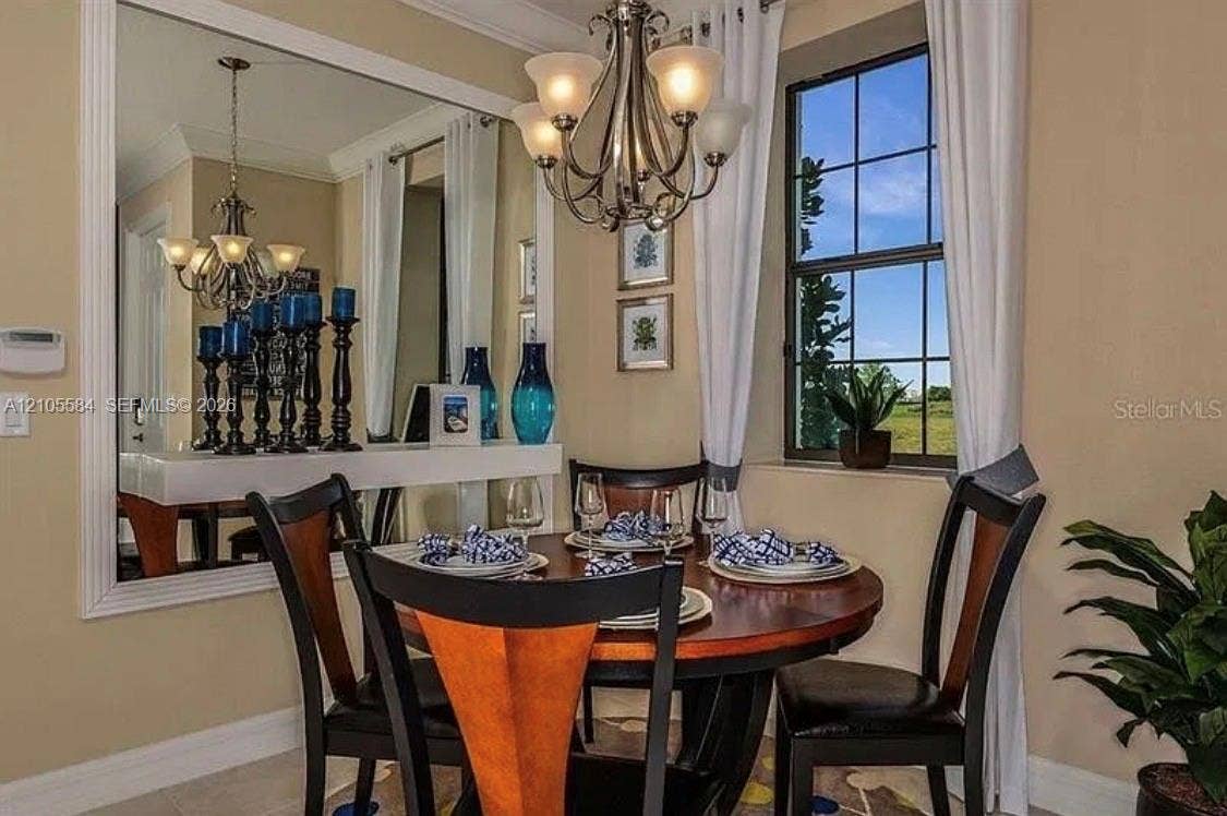 10197 Eagle Creek Center Boulevard, Orlando, FL 32832 Dining area featuring crown molding, a large wall-mounted mirror with decorative trim, a multi-arm chandelier, and a multi-pane window