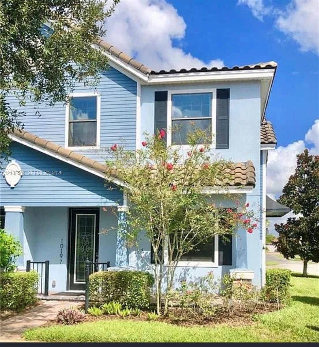 10197 Eagle Creek Center Boulevard, Orlando, FL 32832 Two-story exterior featuring a mix of horizontal lap siding and smooth stucco finish, clay tile roof sections, decorative window shutters, and a glass-paneled entry door