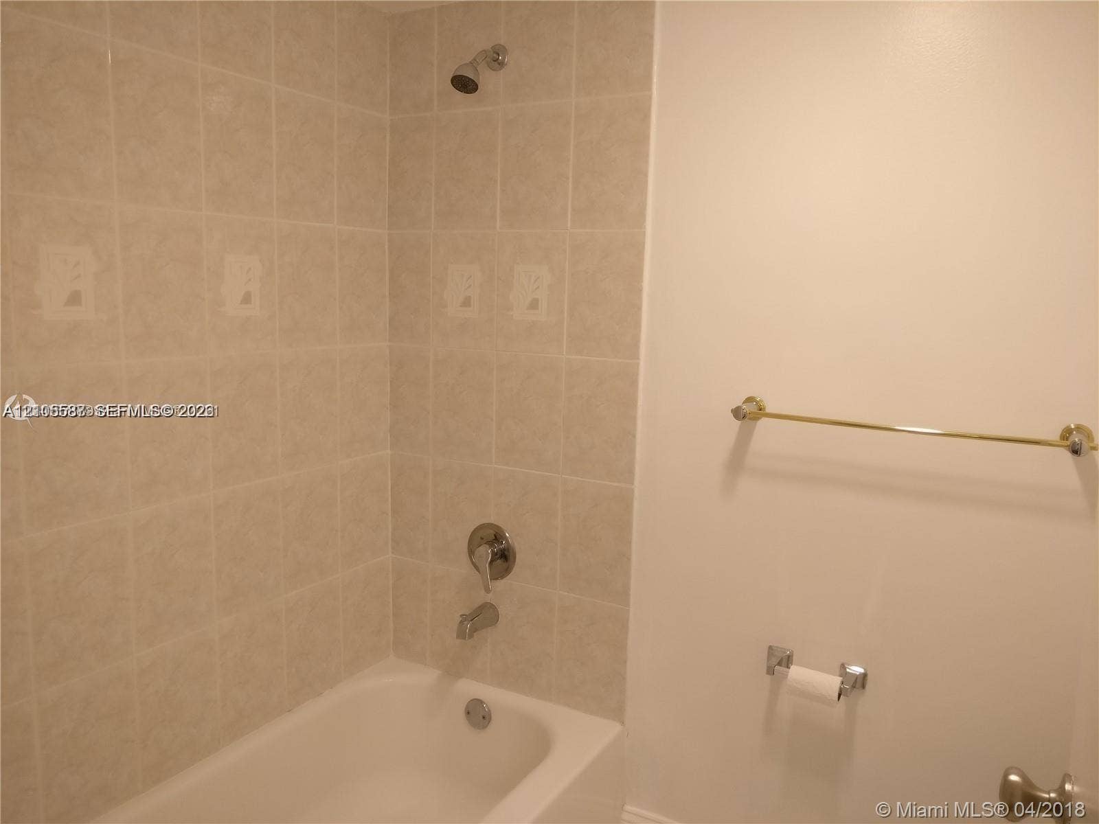 Bathtub with chrome fixtures, tiled shower surround, and a wall-mounted shower head
