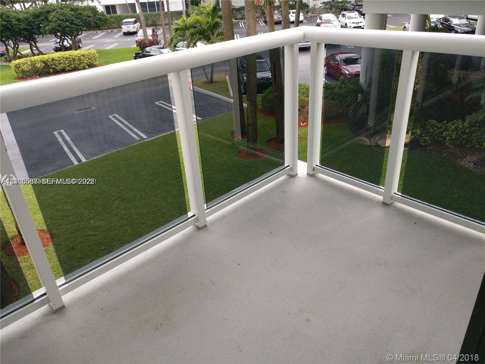 Balcony featuring a solid surface floor, glass panel railing, and white railing frame
