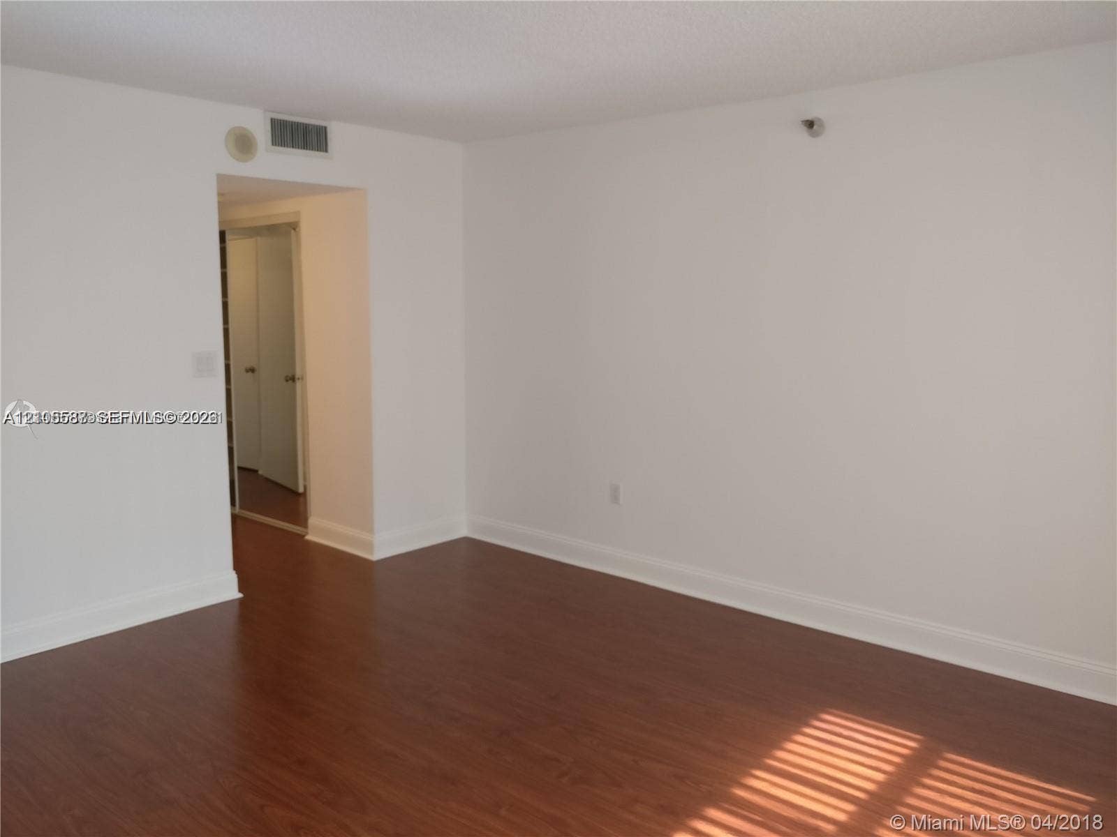 Wood-finish flooring with white baseboards and an arched doorway
