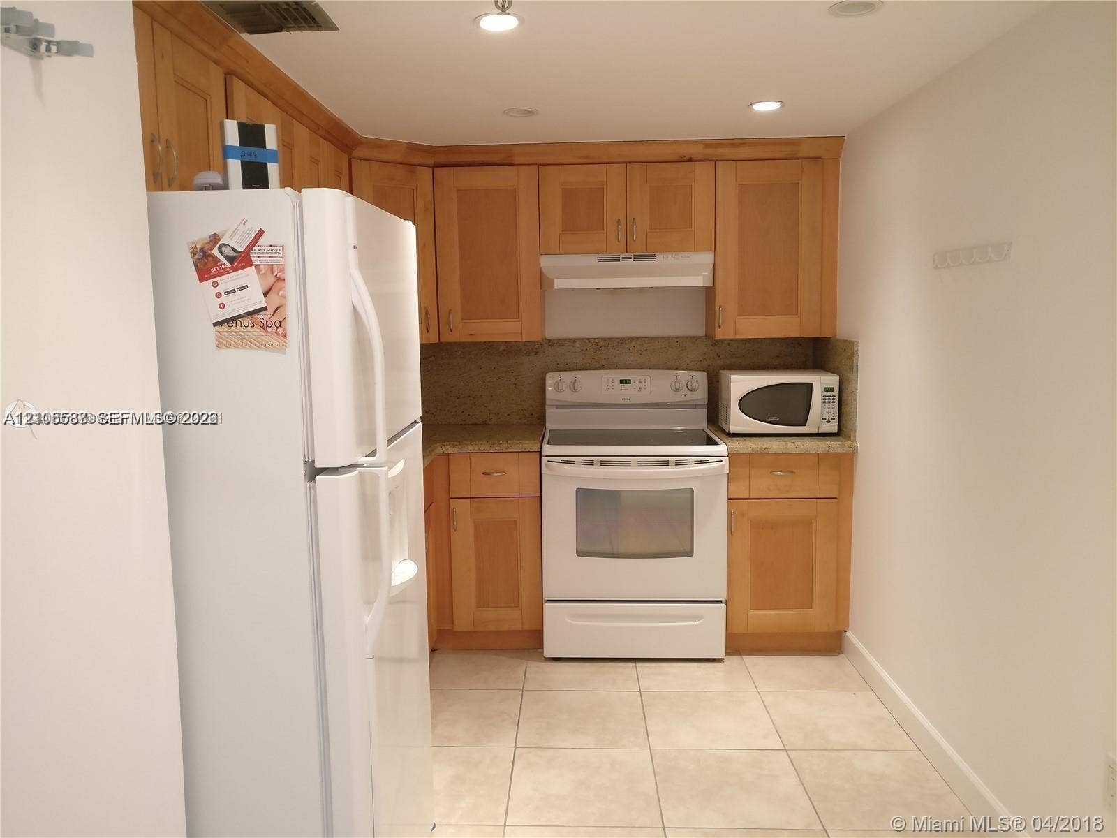 Kitchen featuring wood cabinetry, stone countertops, and tile flooring