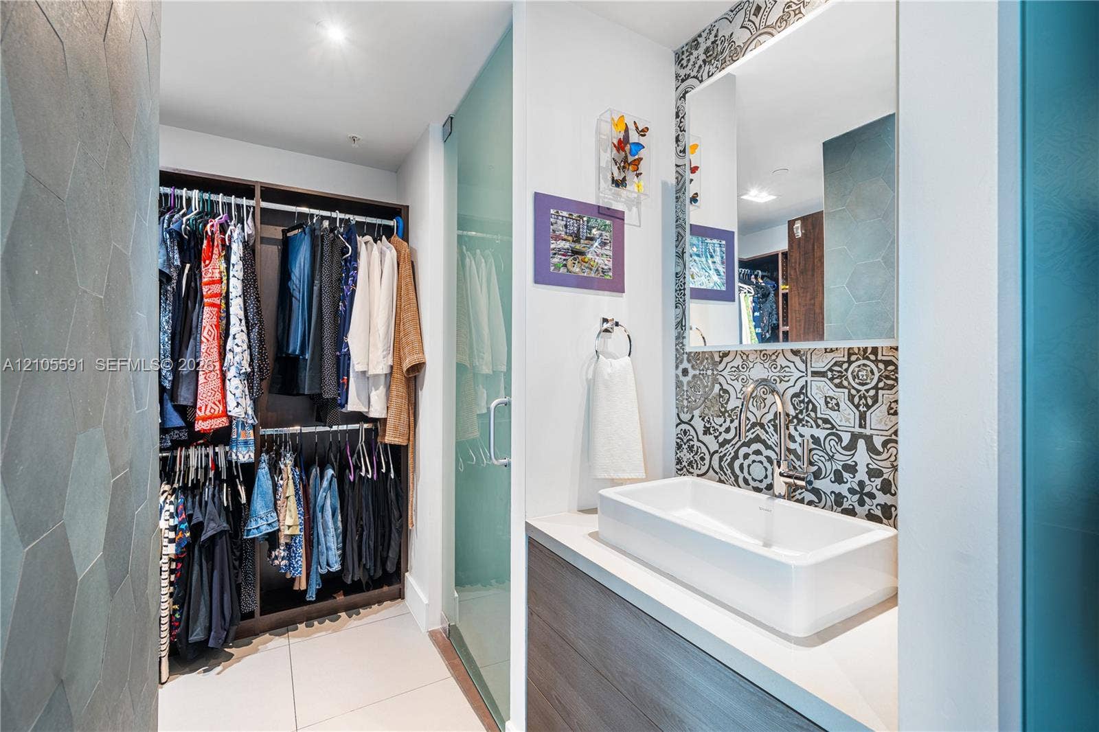 Built-in closet system, tile flooring, glass shower enclosure, vanity with basin sink, and patterned wall tile