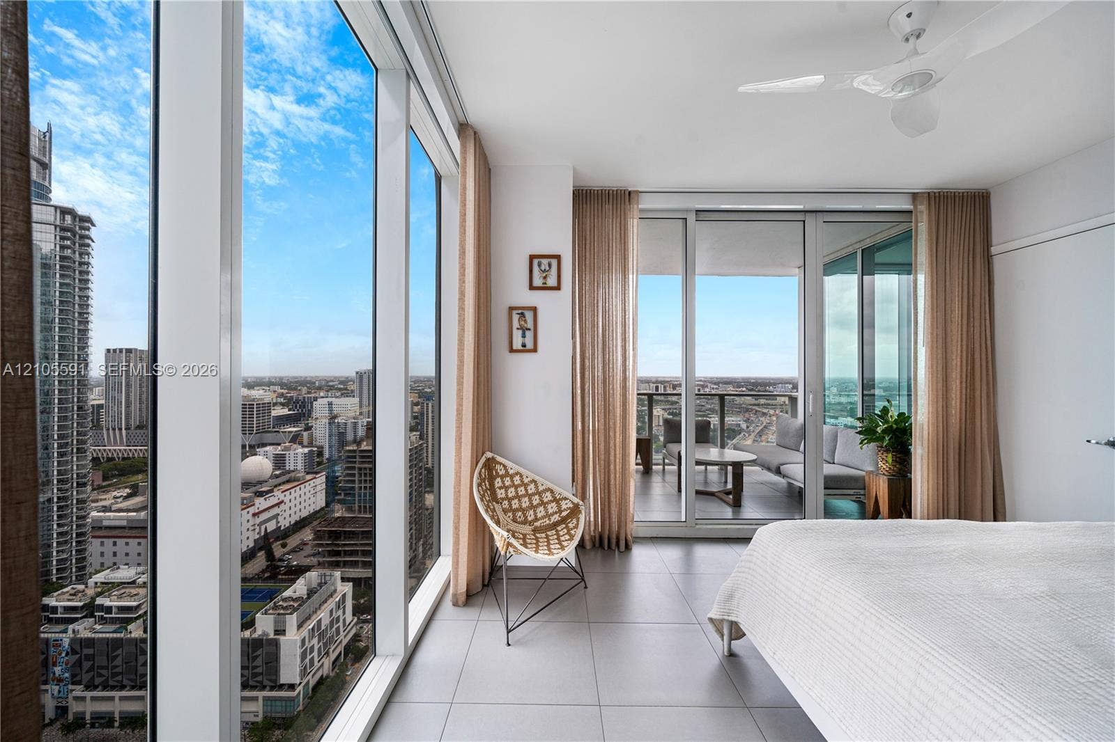 Floor-to-ceiling windows, sliding glass door to a private balcony, ceiling fan, and tiled flooring