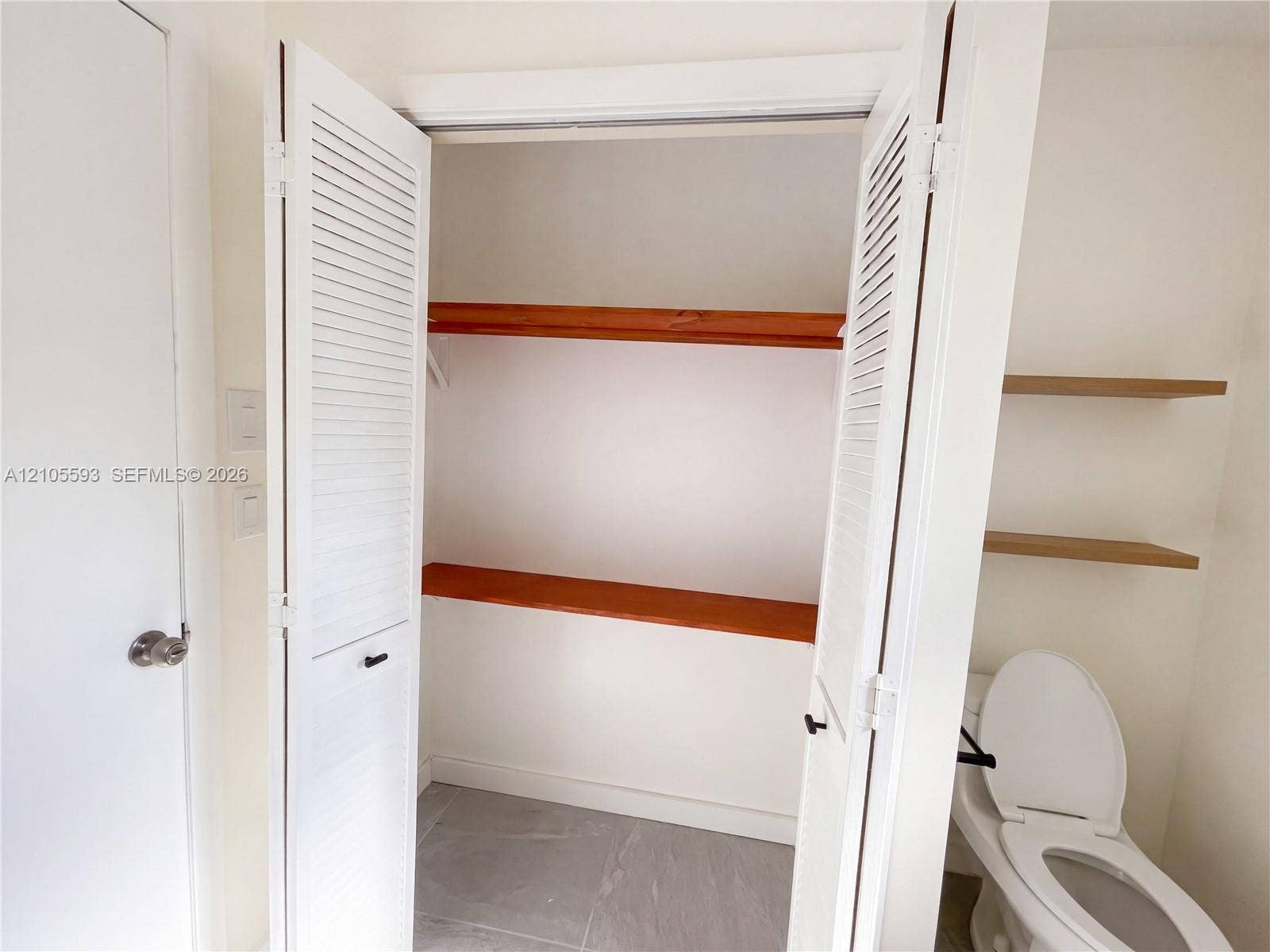 597 Grace Street, Sebastian, FL 32958 Double louvered closet doors, integrated wood shelving, tile flooring, and wall-mounted wood floating shelves