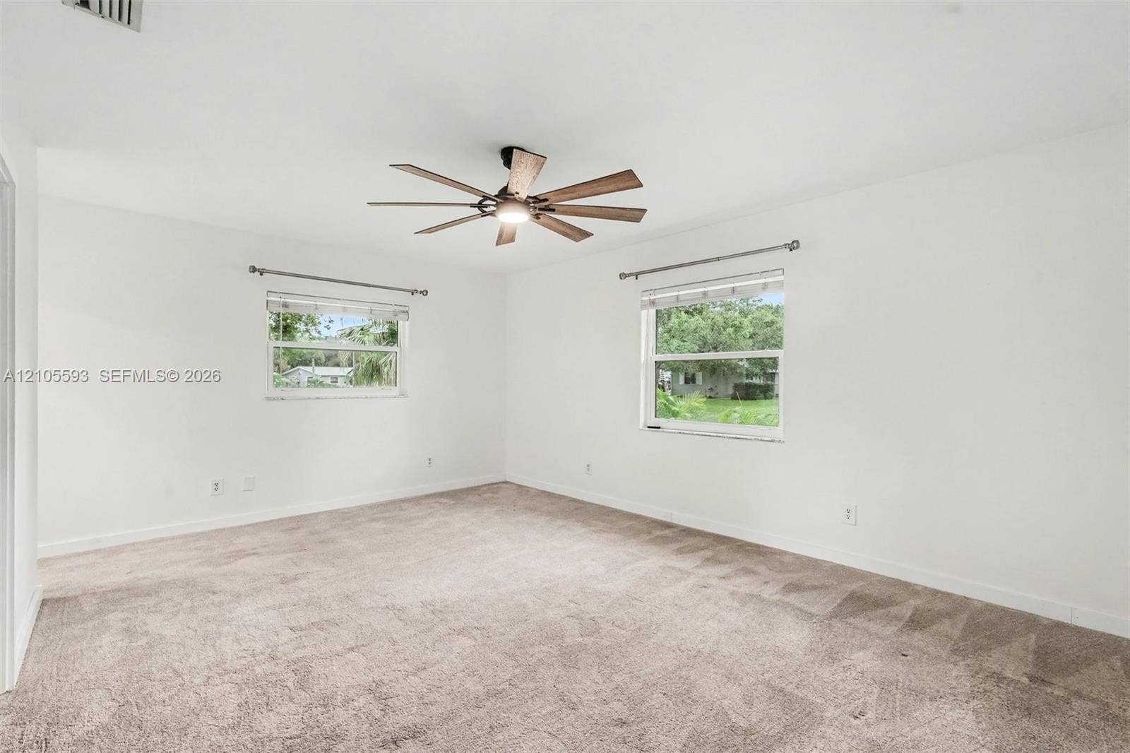 597 Grace Street, Sebastian, FL 32958 Neutral-toned wall-to-wall carpeting, ceiling fan with integrated lighting, dual windows with curtain hardware, and crisp white wall finishes