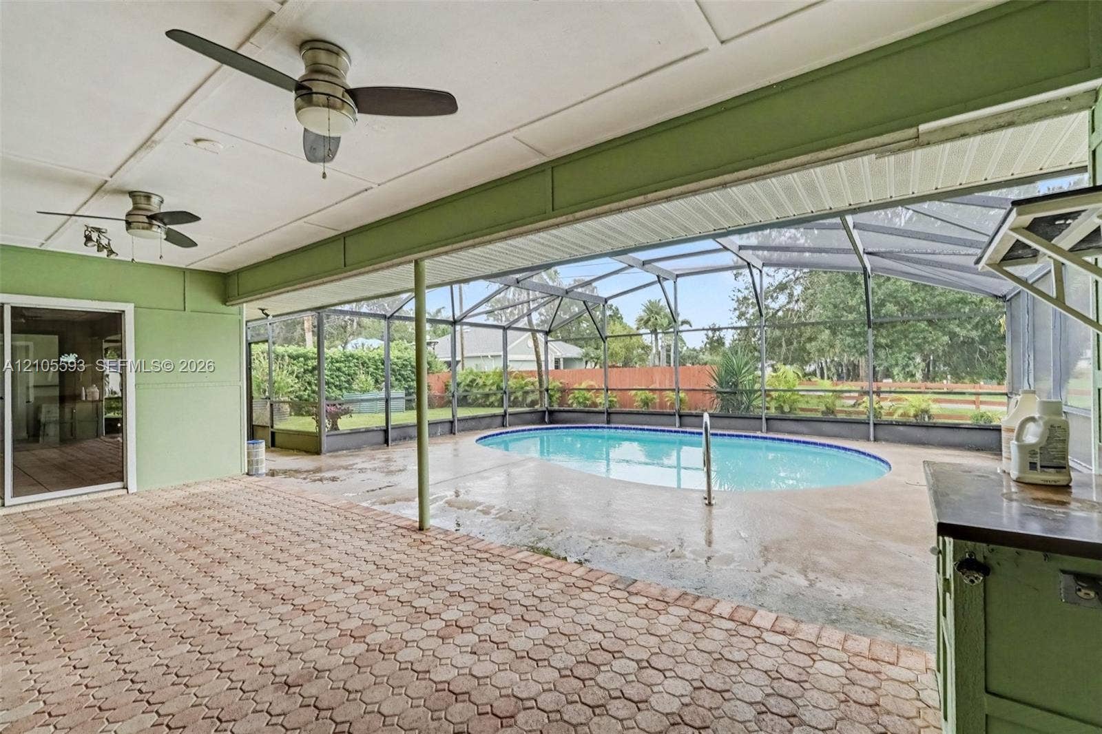 597 Grace Street, Sebastian, FL 32958 Covered patio featuring paver flooring, dual ceiling fans, a screened-in enclosure, and a swimming pool