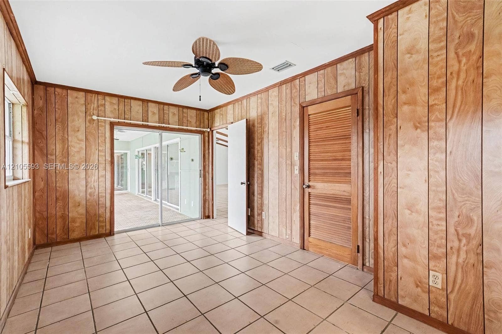 597 Grace Street, Sebastian, FL 32958 Wood-paneled wall finishes, tile flooring, louvered closet door, and ceiling fan