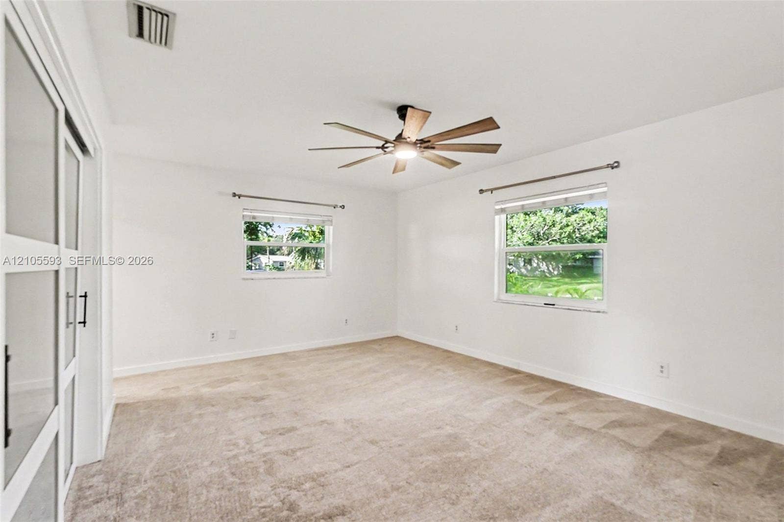 597 Grace Street, Sebastian, FL 32958 Neutral-toned carpeting, ceiling-mounted paddle fan, and sliding glass-panel door with matte black hardware