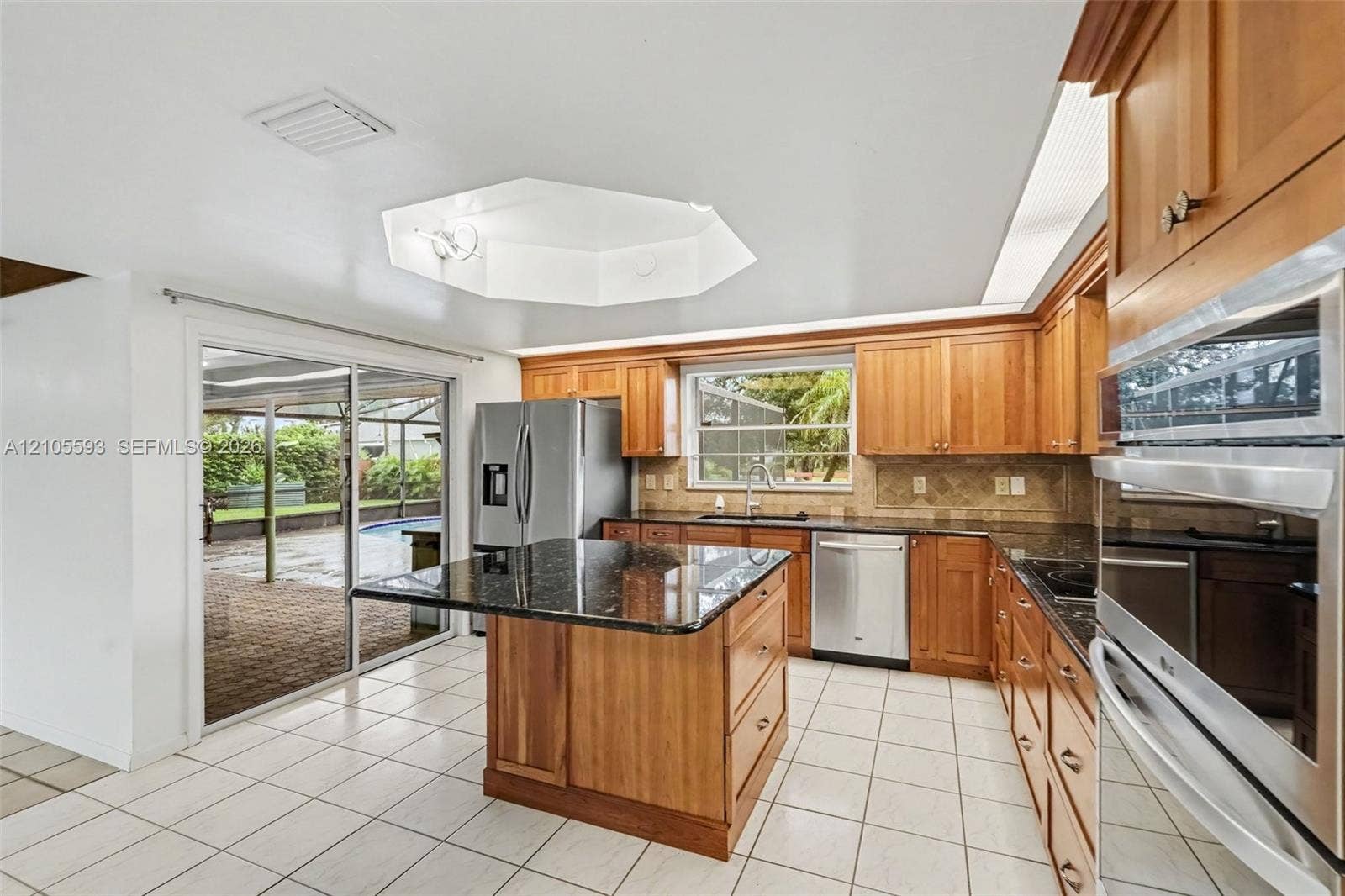 597 Grace Street, Sebastian, FL 32958 Kitchen featuring wood cabinetry, stone countertops, central island, stainless steel appliances, and tile flooring