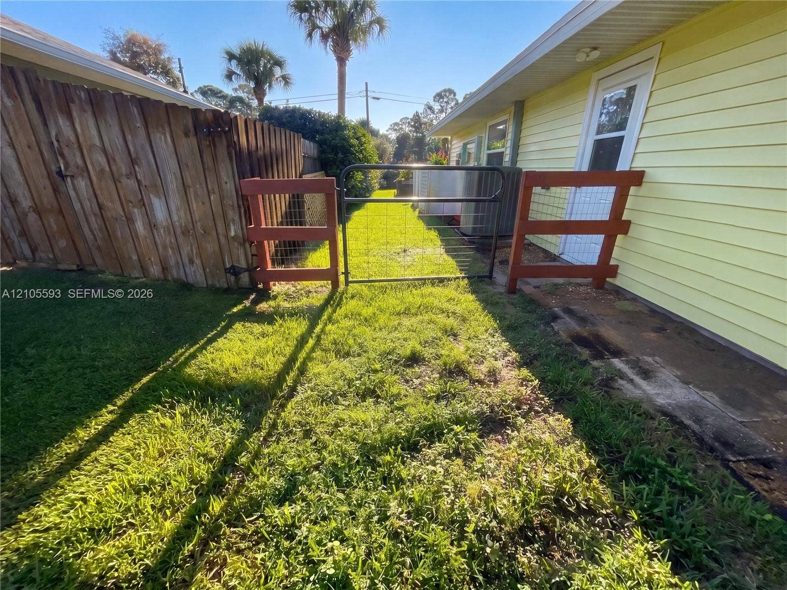 597 Grace Street, Sebastian, FL 32958 Exterior space featuring horizontal siding, a fenced side yard, a metal swing gate, and a concrete pathway