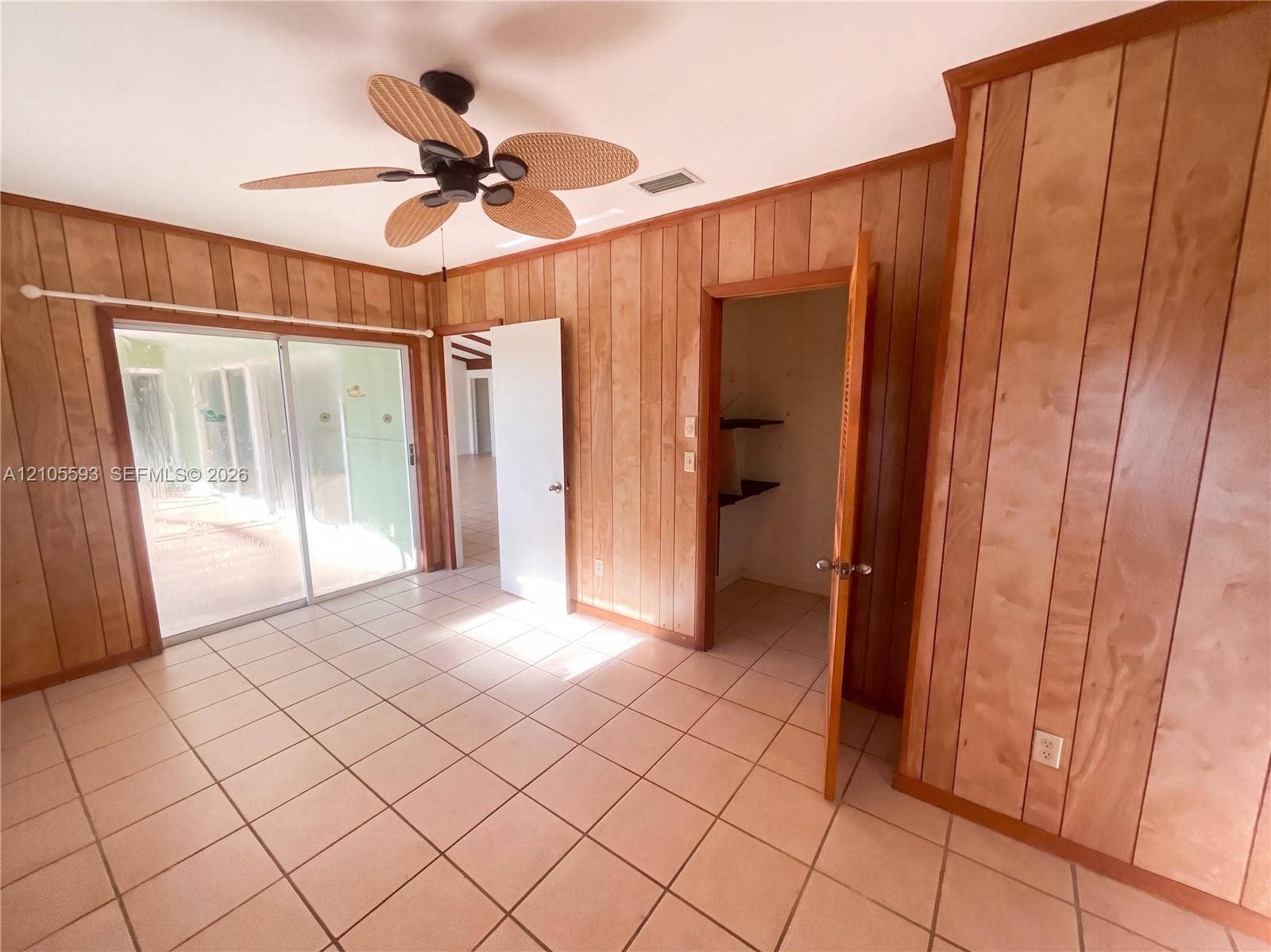 597 Grace Street, Sebastian, FL 32958 Interior featuring wood-paneled walls, tile flooring, sliding glass doors, and a ceiling fan with integrated lighting