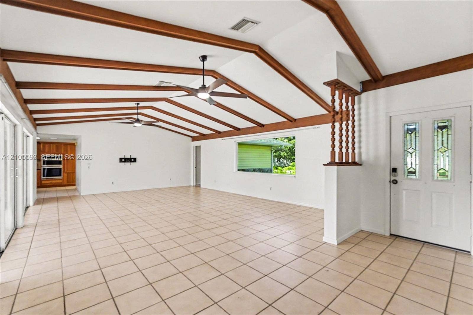 597 Grace Street, Sebastian, FL 32958 Vaulted ceiling featuring exposed wood beams, ceramic tile flooring, built-in dual wall ovens, ceiling fans, and an exterior door with glass panel inserts