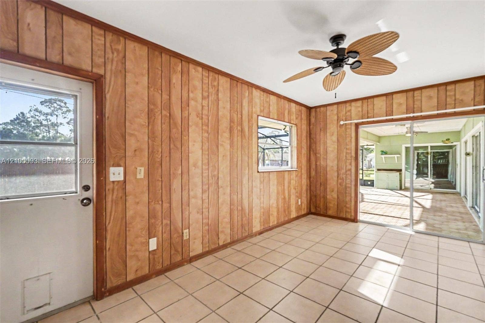 597 Grace Street, Sebastian, FL 32958 Room featuring wood-panel wall finishes, tile flooring, a multi-blade ceiling fan, a window with exterior exposure, and sliding glass doors