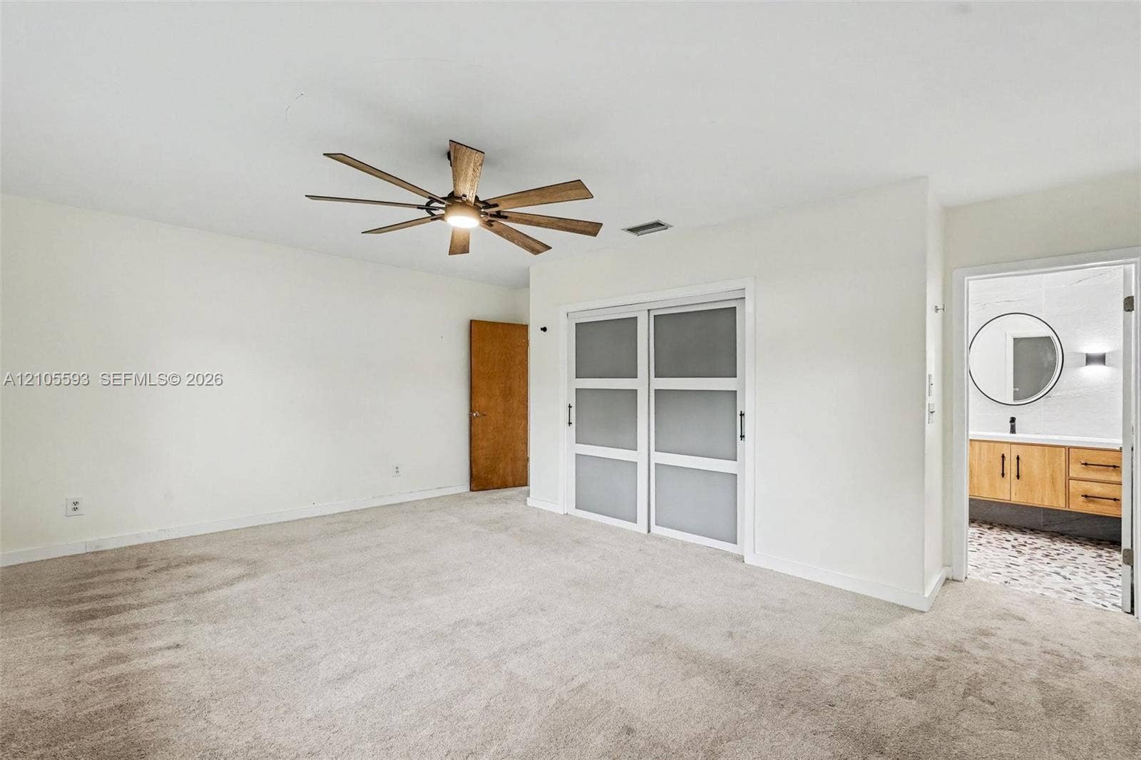 597 Grace Street, Sebastian, FL 32958 Room featuring neutral wall-to-wall carpeting, ceiling fan with integrated lighting, and dual-panel sliding doors with frosted glass inserts