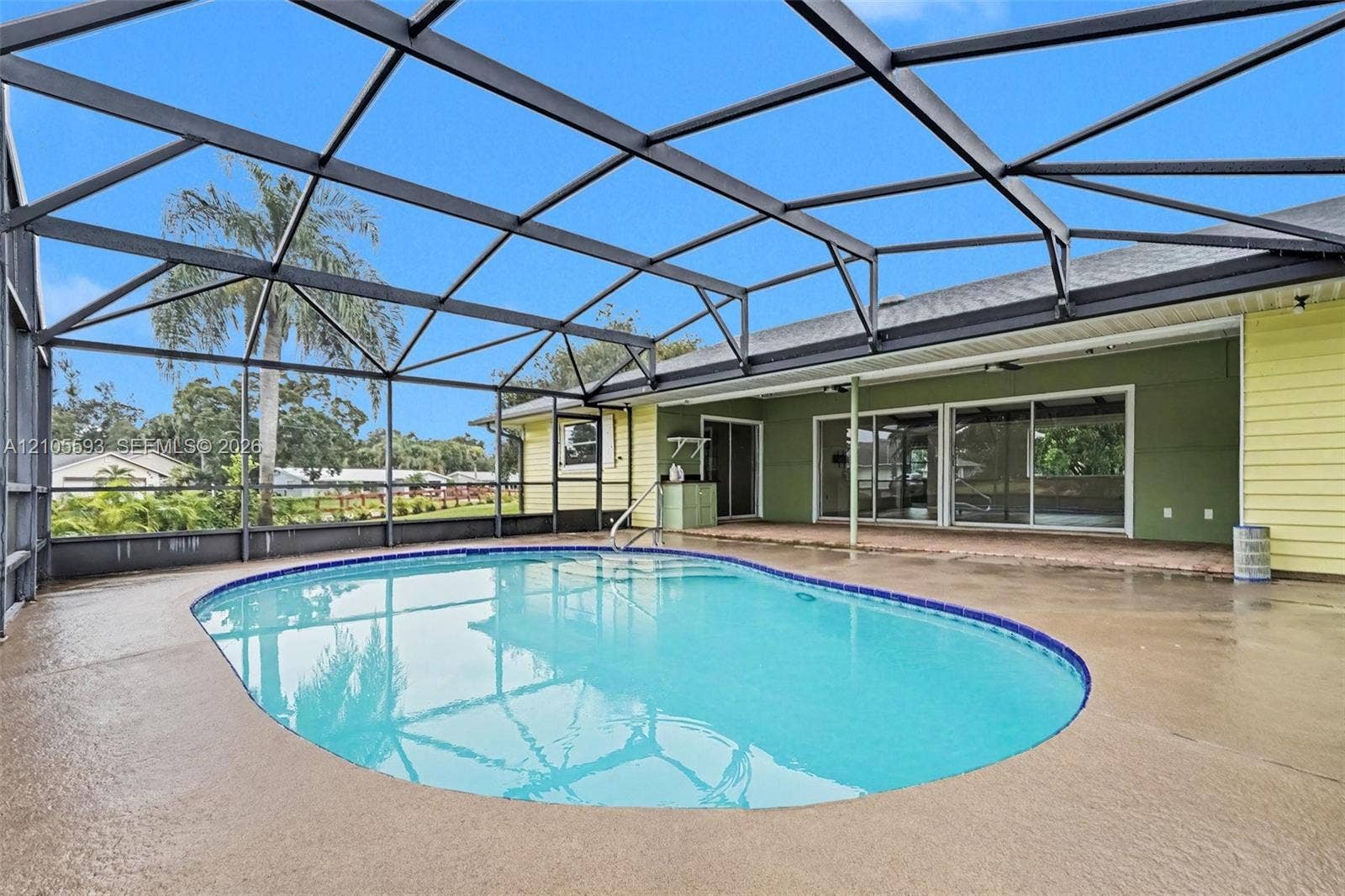 597 Grace Street, Sebastian, FL 32958 Screened-in patio featuring a concrete pool deck, private swimming pool with tile trim, and sliding glass door access to the residence