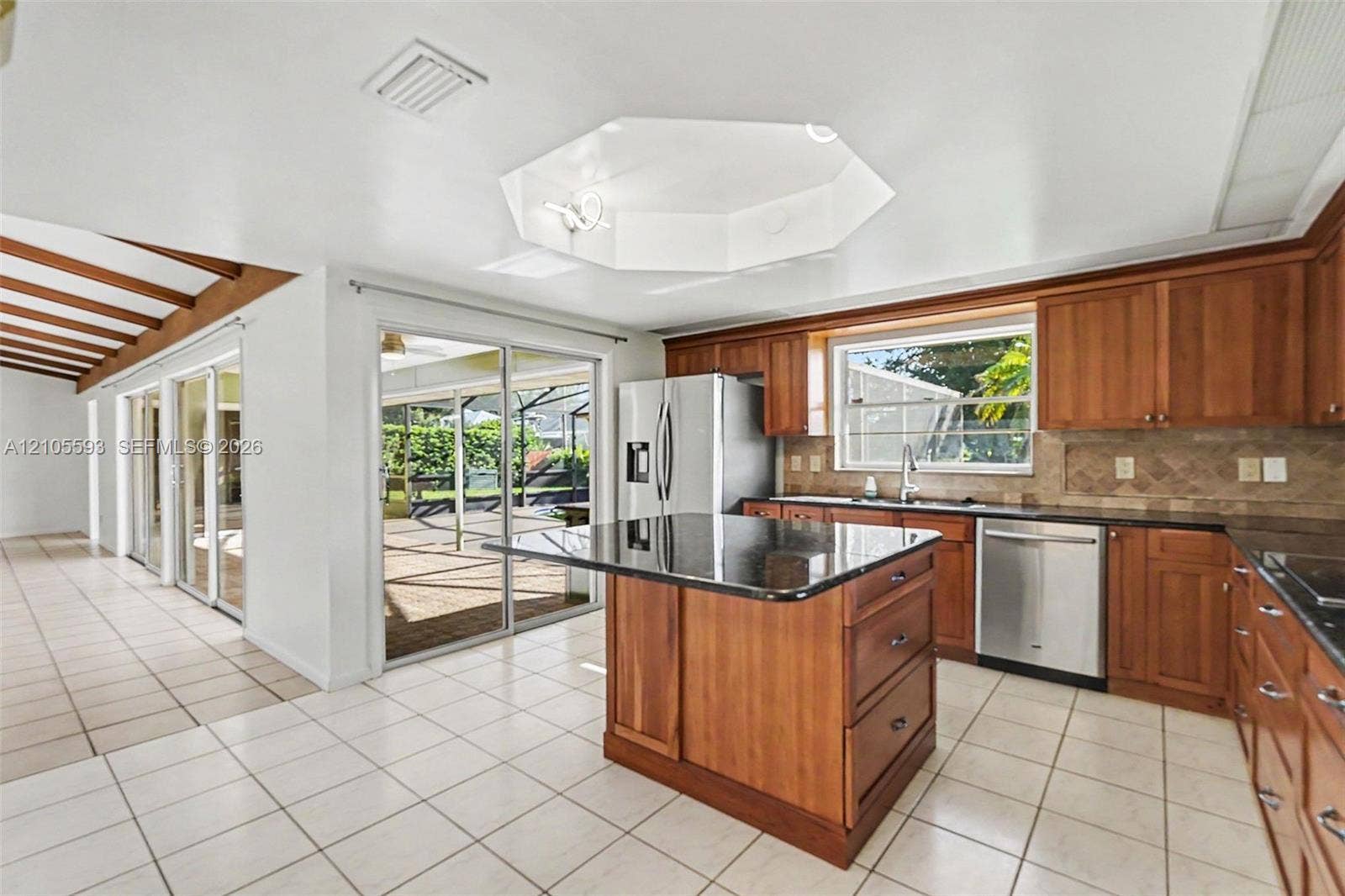 597 Grace Street, Sebastian, FL 32958 Kitchen featuring stained wood cabinetry, stone countertops, central island, tiled flooring, and vaulted ceiling with recessed lighting