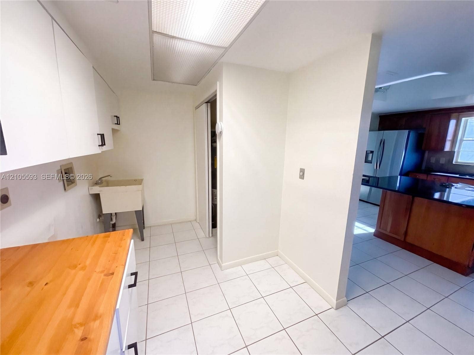 597 Grace Street, Sebastian, FL 32958 Utility space featuring white cabinetry, a butcher-block countertop, and a wall-mounted utility sink with tiled flooring
