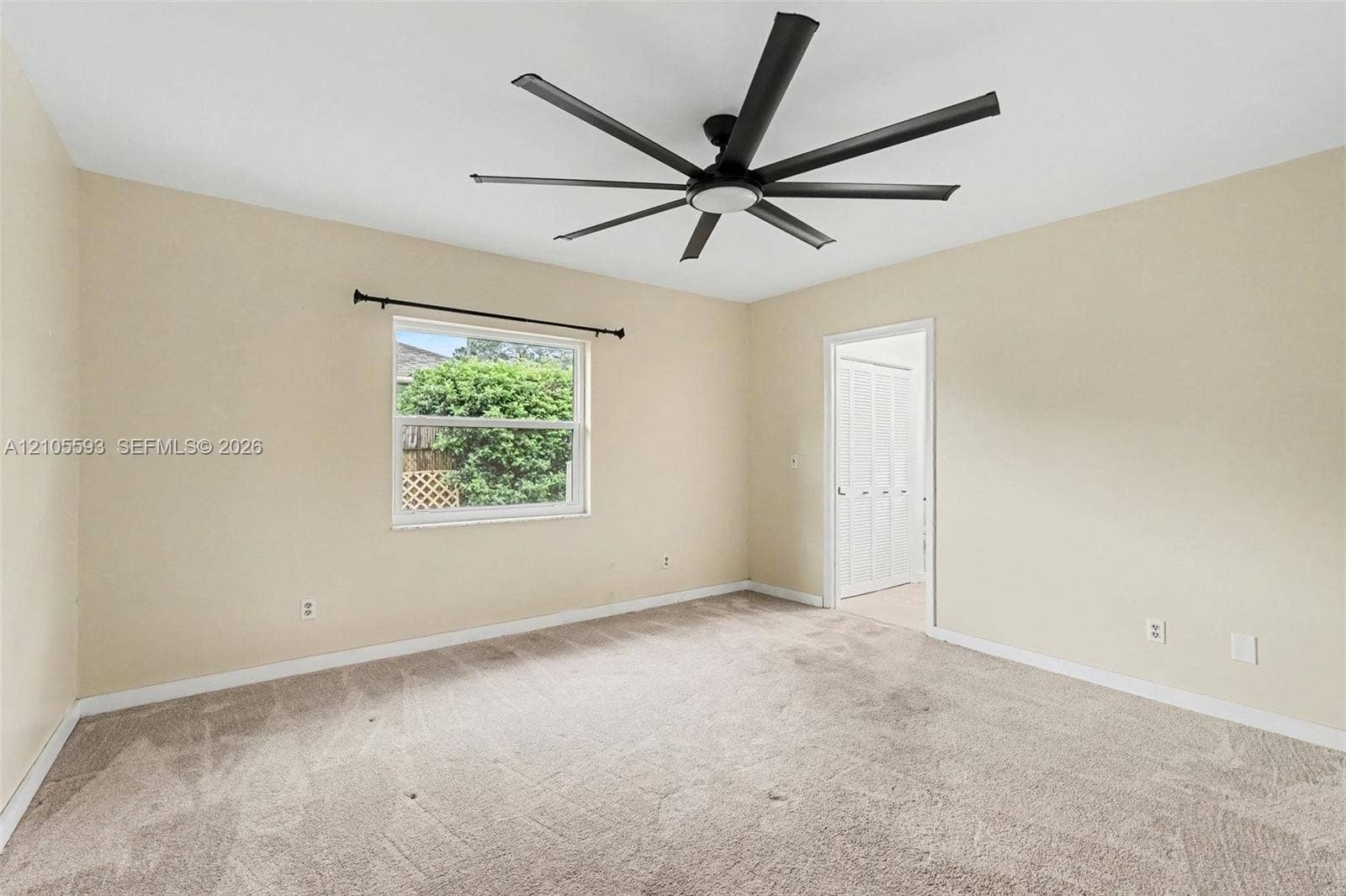 597 Grace Street, Sebastian, FL 32958 Neutral-toned room featuring wall-to-wall carpeting, a multi-blade ceiling fan, and a window with a metal rod