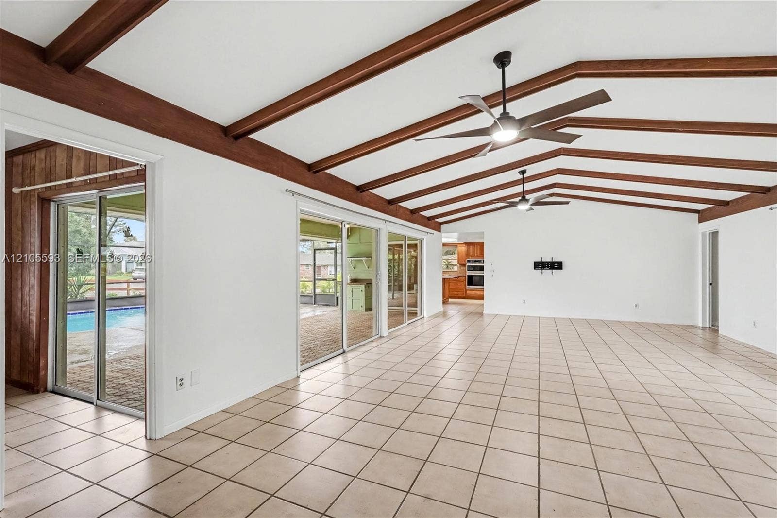 597 Grace Street, Sebastian, FL 32958 Vaulted ceiling featuring exposed wood beams, ceramic tile flooring, dual ceiling fans, and expansive sliding glass doors