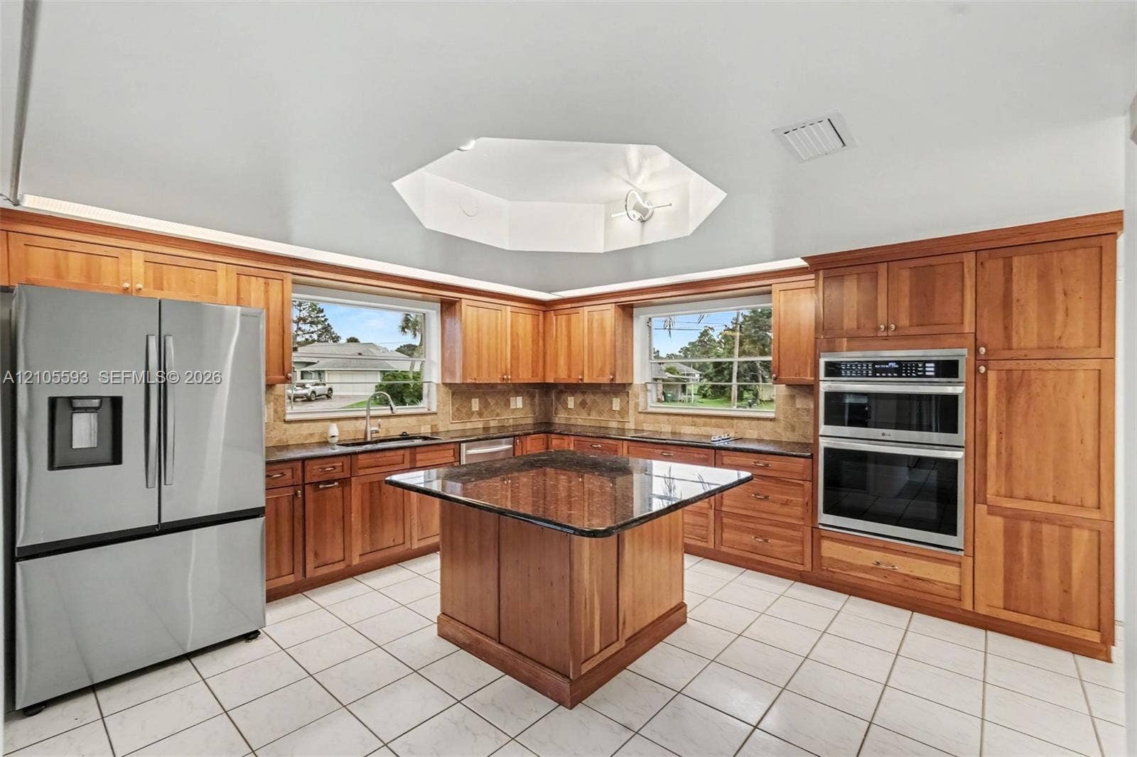 597 Grace Street, Sebastian, FL 32958 Kitchen featuring custom wood cabinetry, central island with stone countertop, stainless steel double wall oven, stainless steel refrigerator, and vaulted octagonal ceiling