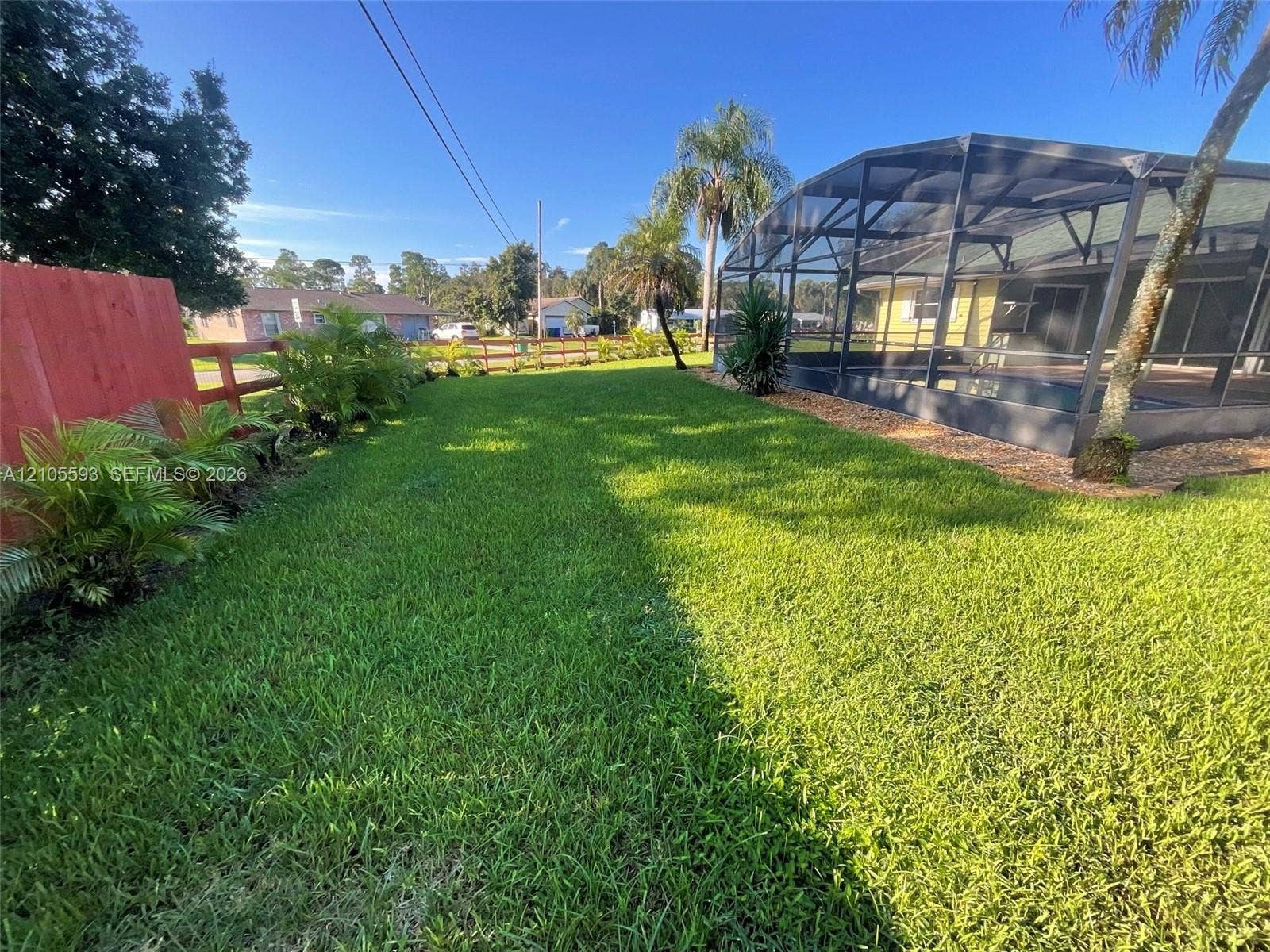 597 Grace Street, Sebastian, FL 32958 Fenced backyard featuring a manicured lawn, landscaping, and a screened-in pool enclosure