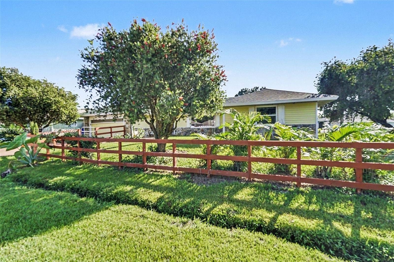 597 Grace Street, Sebastian, FL 32958 Single-story residence featuring horizontal lap siding, stone veneer accents, a multi-tiered wooden rail fence, and established landscaping