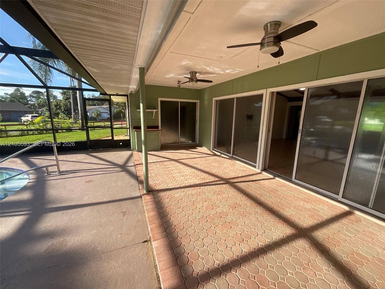 597 Grace Street, Sebastian, FL 32958 Screened-in lanai featuring paver flooring, dual ceiling fans, sliding glass doors, and an integrated pool area