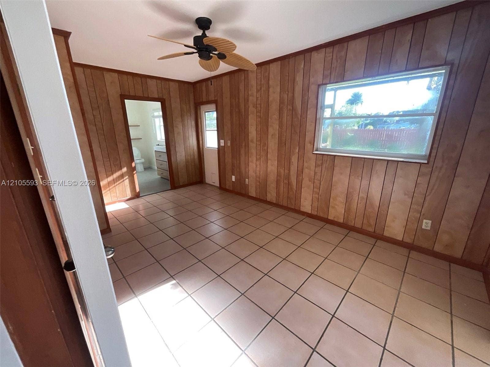 597 Grace Street, Sebastian, FL 32958 Interior space featuring wood-paneled walls, neutral-toned square tile flooring, a ceiling fan, and a single-hung window