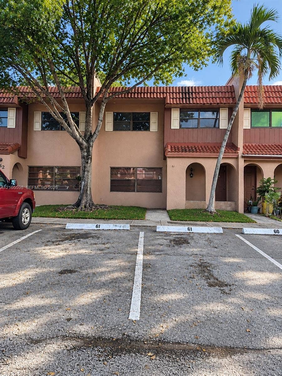 Mediterranean-style architecture with a tile roof, stucco exterior, and white window shutters
