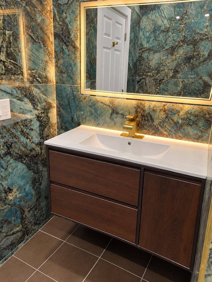 Floating vanity with wood-finish cabinetry, integrated rectangular sink, and gold-finish faucet