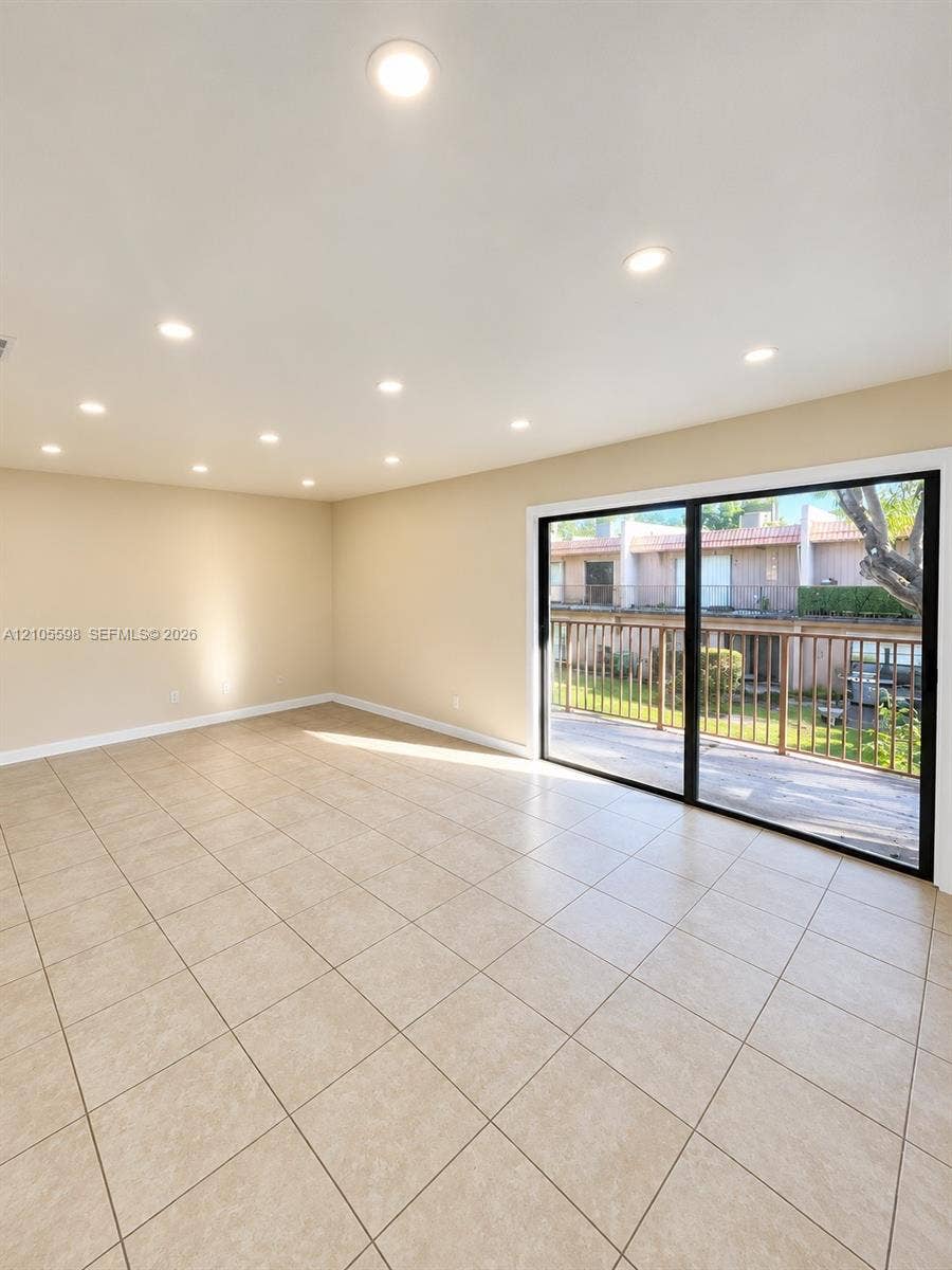 Recessed lighting, neutral wall tones, large format tile flooring, and sliding glass doors with direct outdoor access