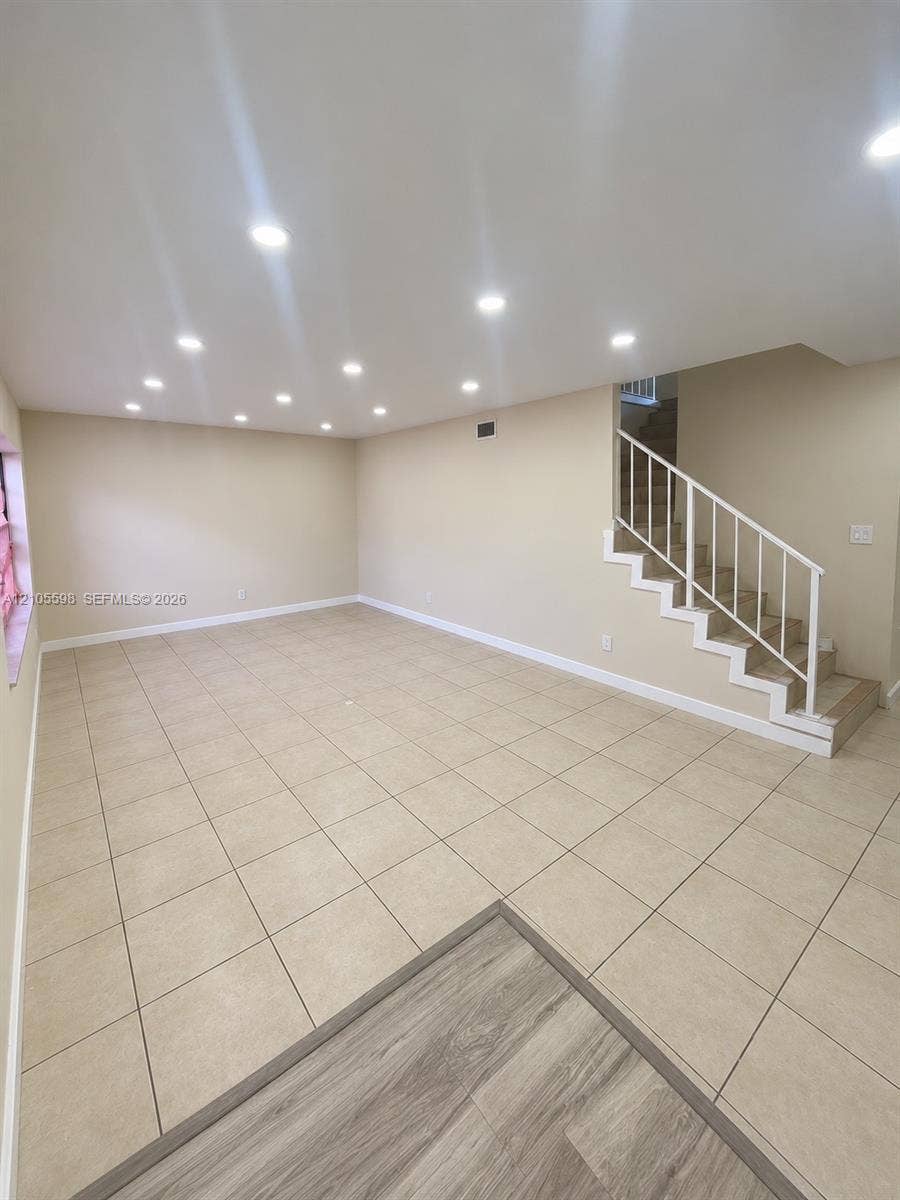 Expansive room featuring recessed lighting, neutral wall tones, and large format floor tiling