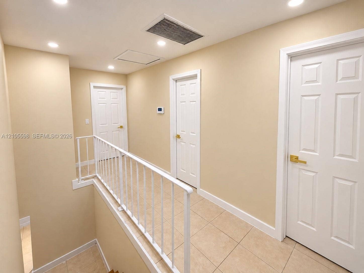 Recessed ceiling lighting, tile flooring, white interior doors, and a white railing