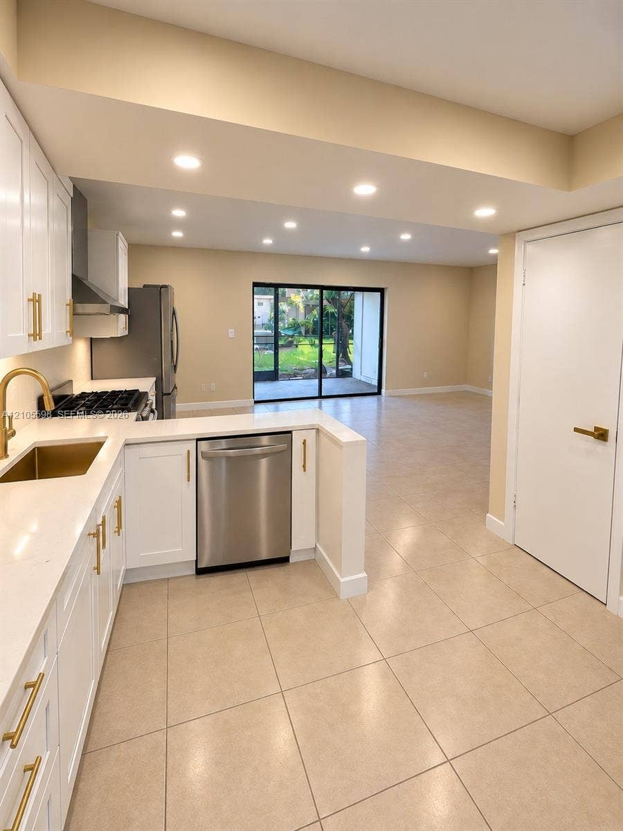 Modern kitchen with white cabinetry, stainless steel appliances, and solid surface countertops