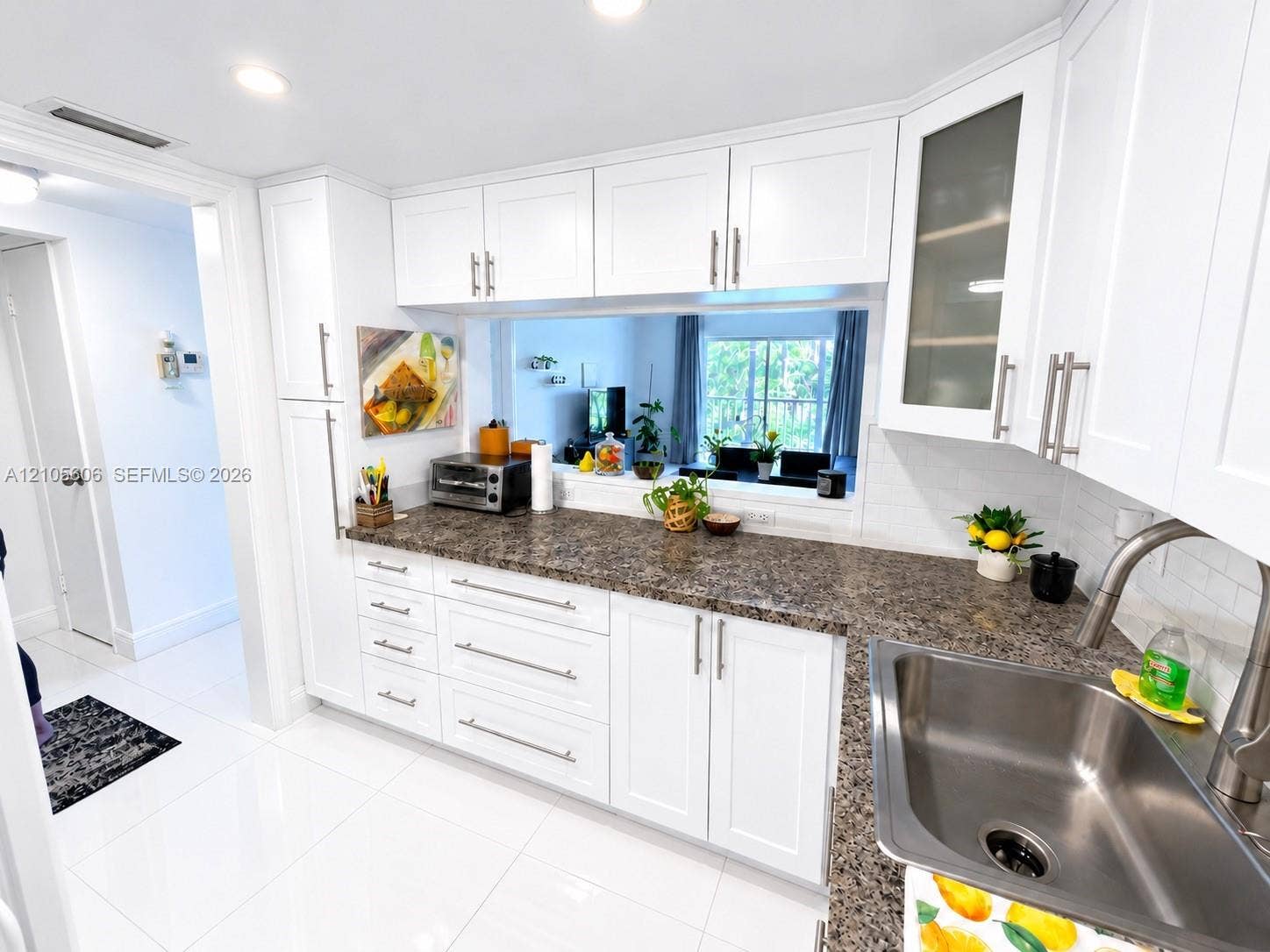 White shaker-style cabinetry with brushed nickel hardware, granite-look countertops, stainless steel sink with a high-arch faucet, white subway tile backsplash, and recessed lighting