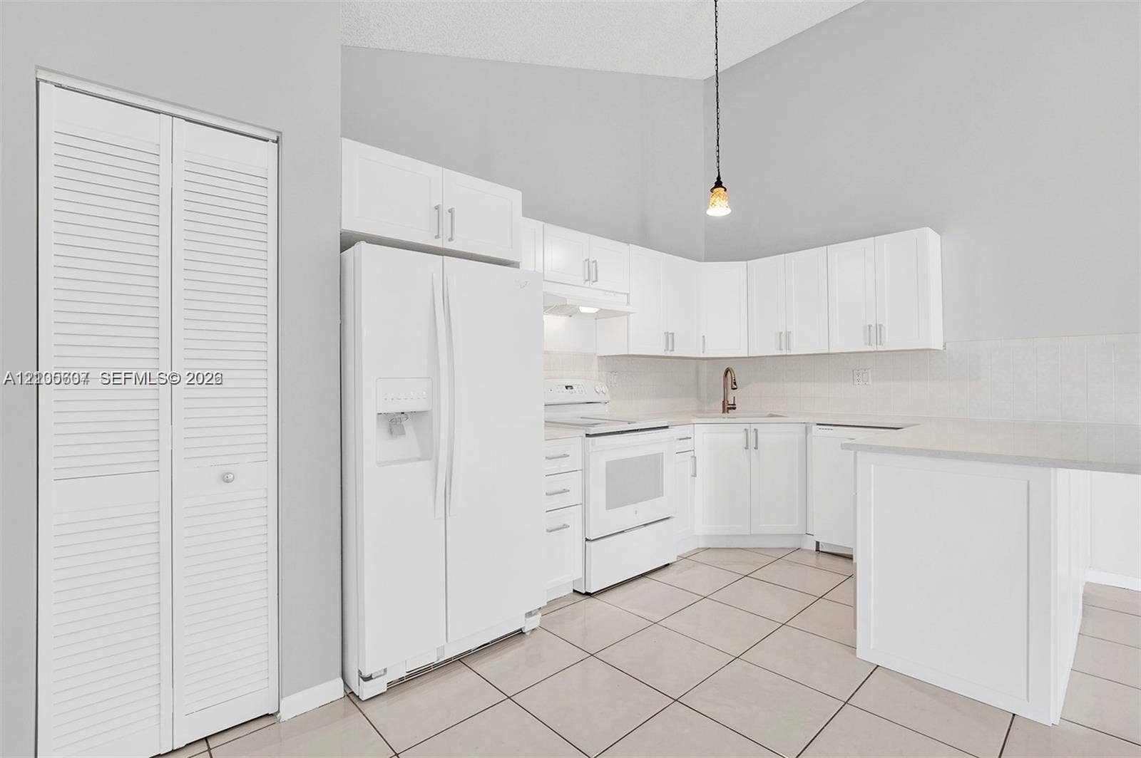 9892 Boca Gardens Parkway, #A, Boca Raton, FL 33496 Vaulted ceiling, white cabinetry, tile flooring, white appliances, and a built-in breakfast bar