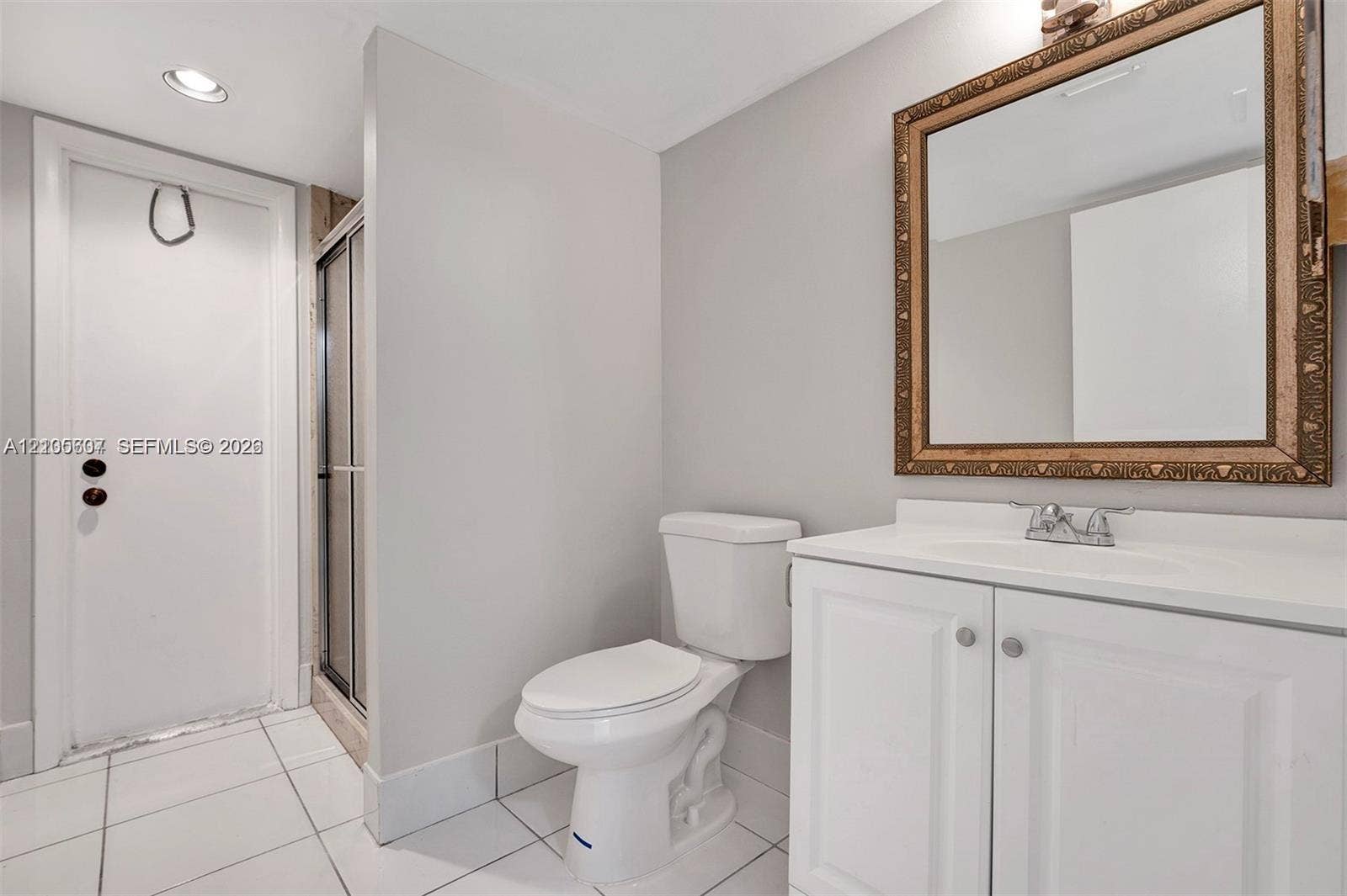 9892 Boca Gardens Parkway, #A, Boca Raton, FL 33496 White panel vanity with a single basin sink, framed mirror, and tiled flooring