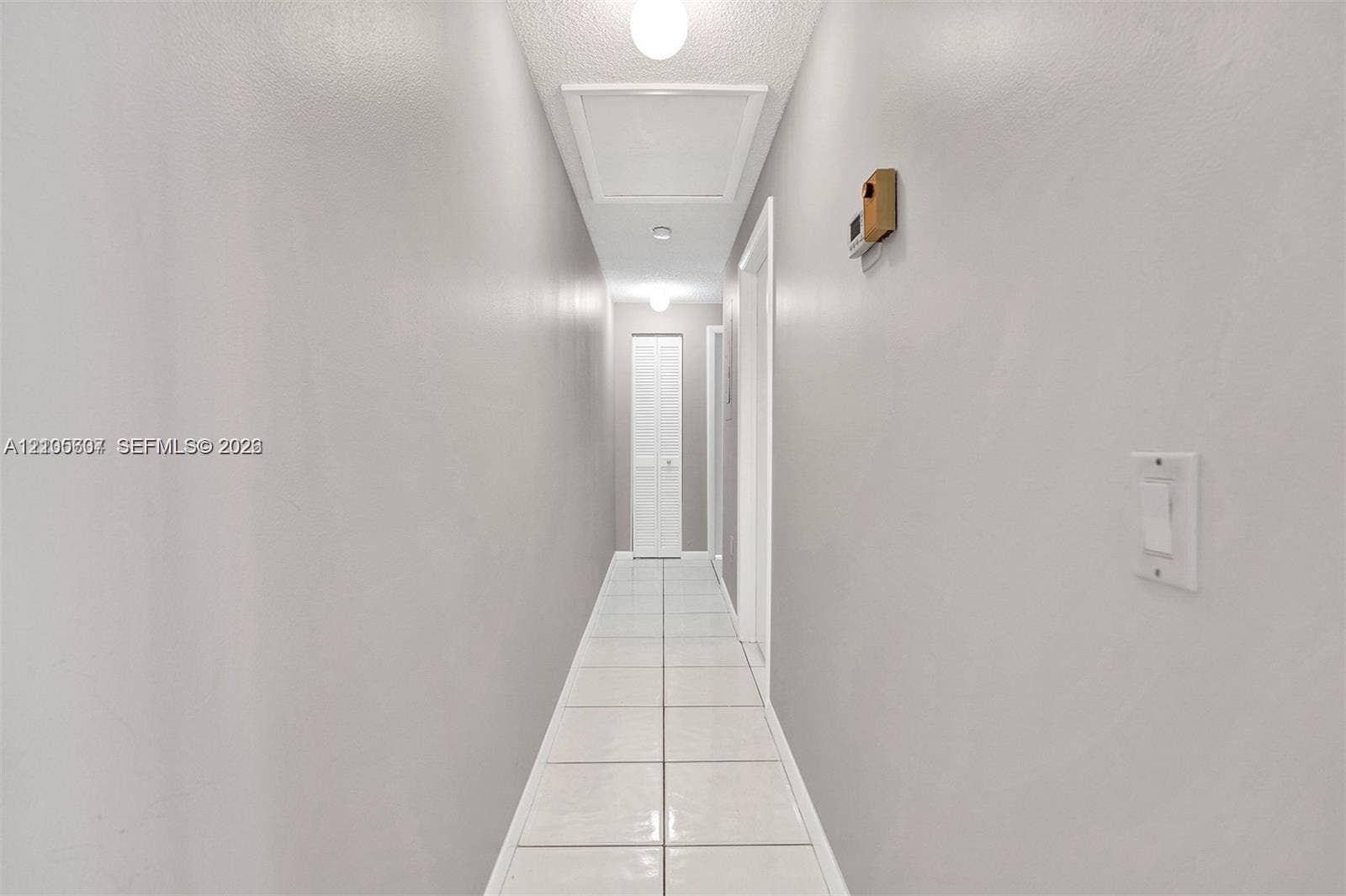 9892 Boca Gardens Parkway, #A, Boca Raton, FL 33496 Hallway with square tile flooring, recessed ceiling lighting, and white walls