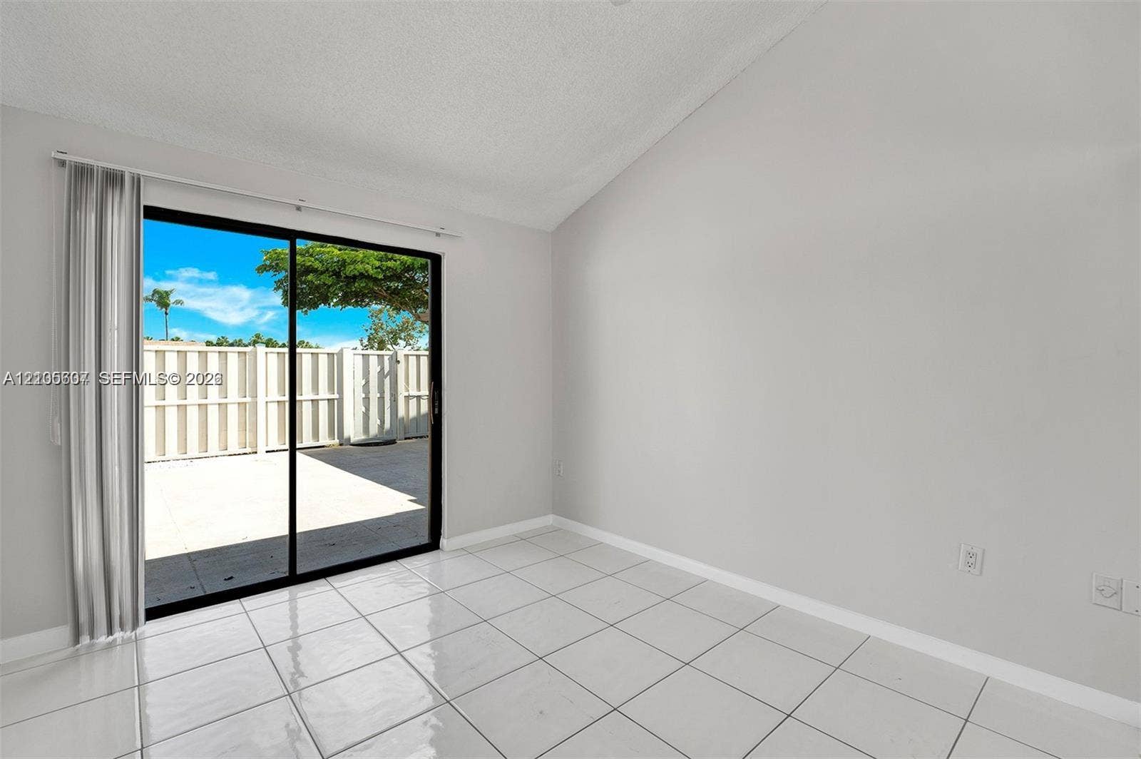 9892 Boca Gardens Parkway, #A, Boca Raton, FL 33496 White tile flooring, vaulted ceiling, sliding glass door, and a private patio
