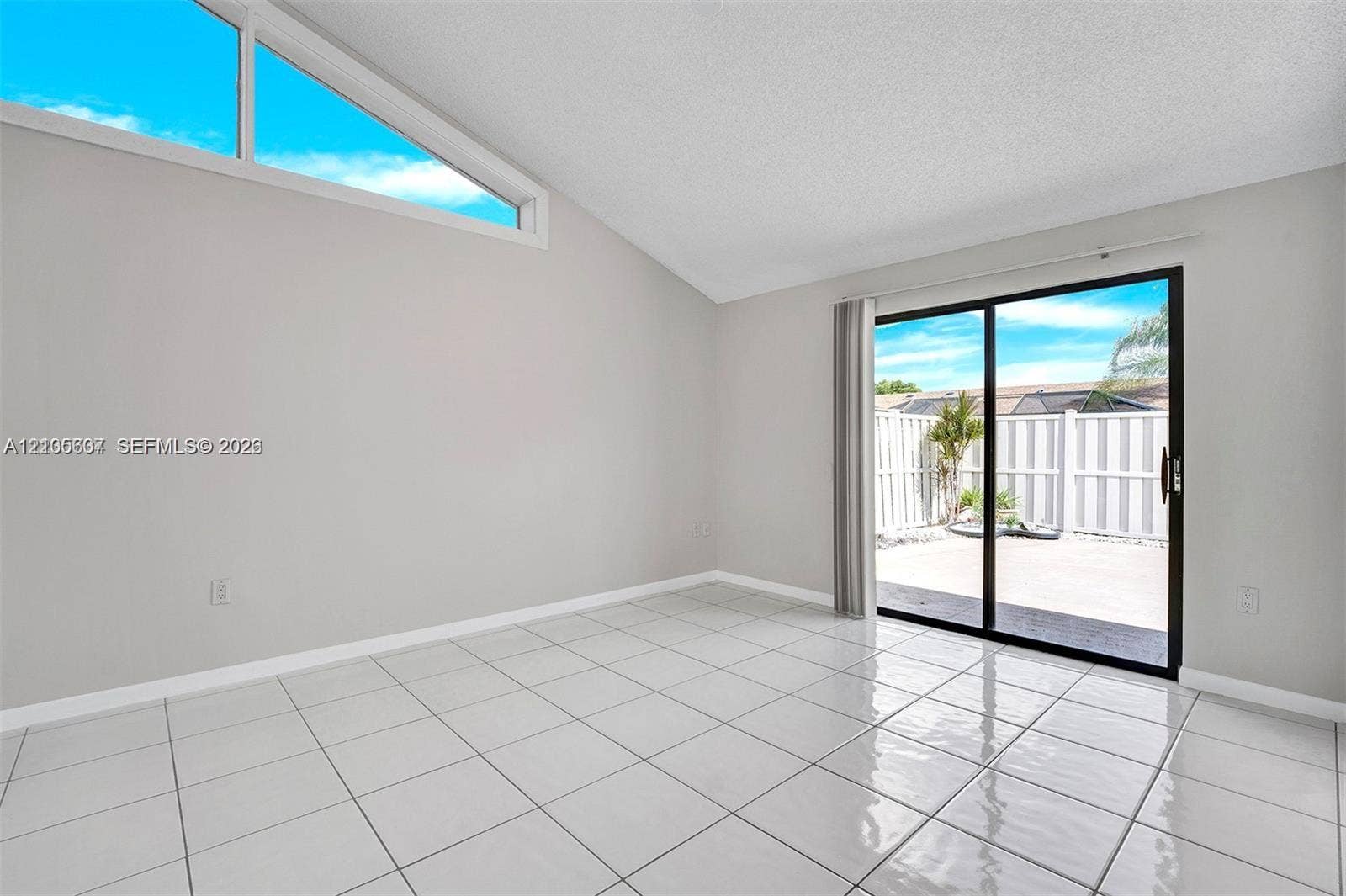 9892 Boca Gardens Parkway, #A, Boca Raton, FL 33496 Vaulted ceiling, high transom window, ceramic tile flooring, sliding glass door, and private patio