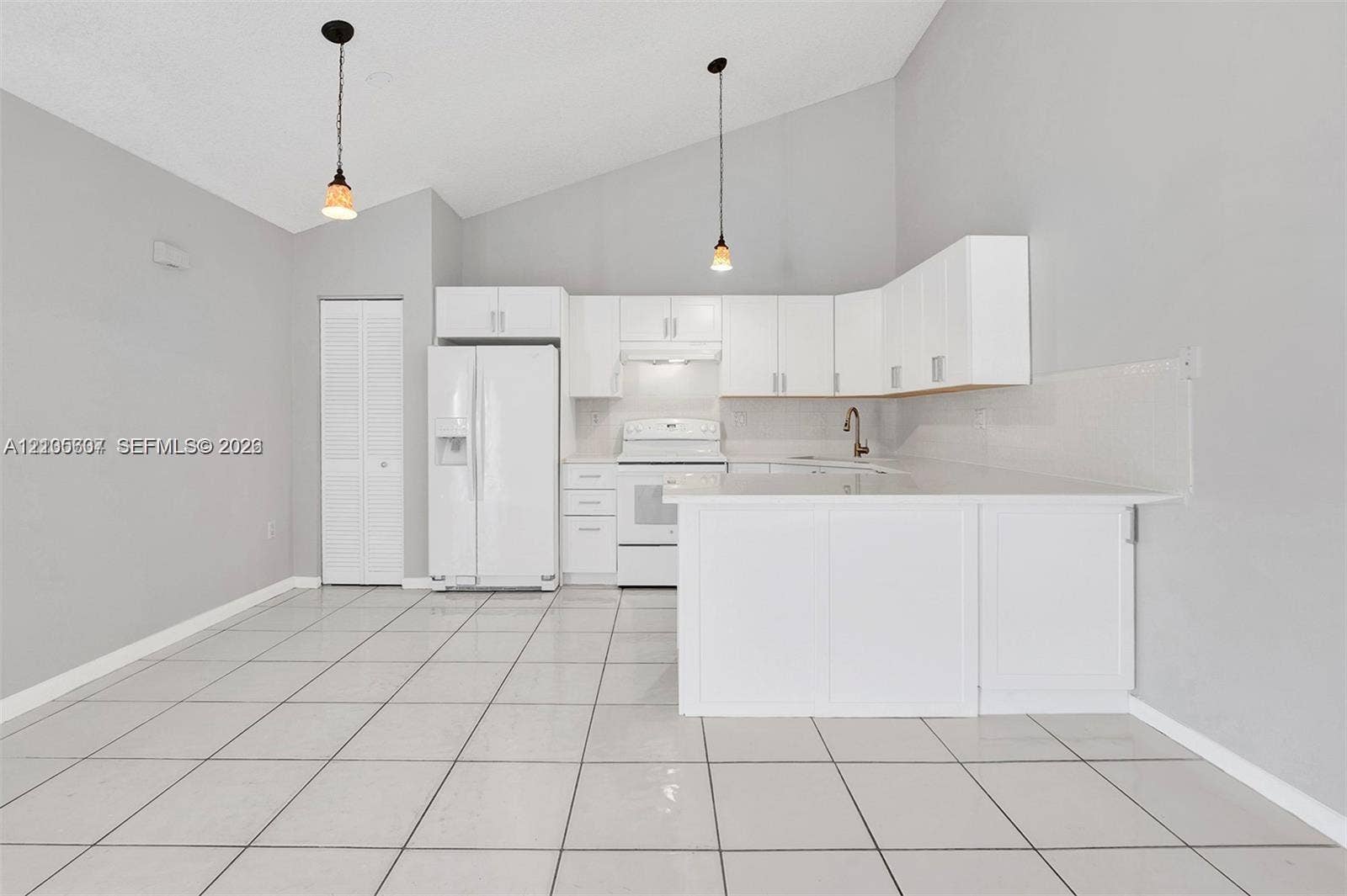 9892 Boca Gardens Parkway, #A, Boca Raton, FL 33496 Vaulted ceilings with pendant lighting, white cabinetry, a kitchen island, and tile flooring