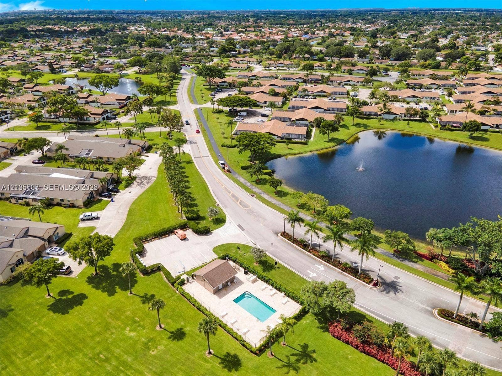9892 Boca Gardens Parkway, #A, Boca Raton, FL 33496 Community setting featuring a central swimming pool, paved roadways, and multiple bodies of water