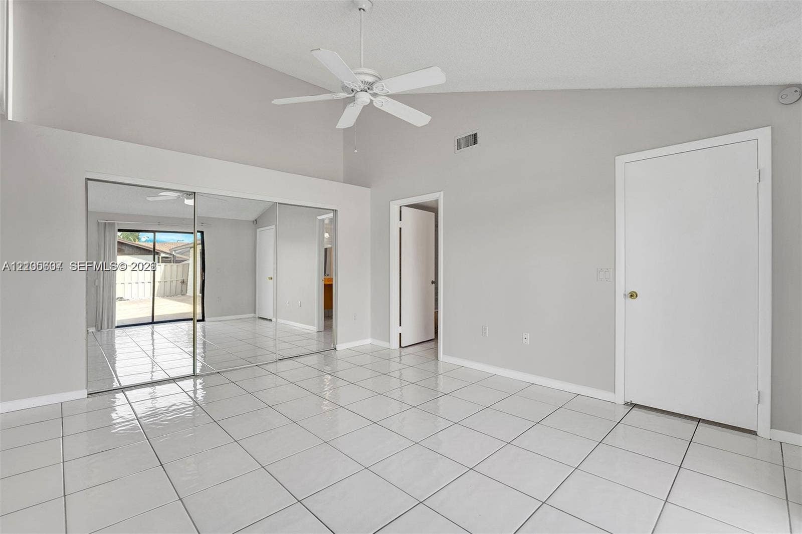 9892 Boca Gardens Parkway, #A, Boca Raton, FL 33496 Vaulted ceiling, white tile flooring, ceiling fan, mirrored closet doors, and sliding glass door