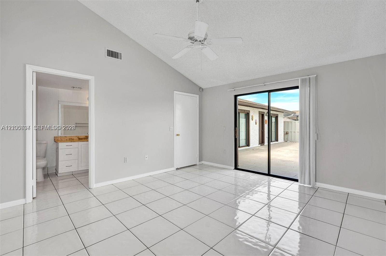 9892 Boca Gardens Parkway, #A, Boca Raton, FL 33496 Vaulted ceiling with a ceiling fan, white tile flooring, and sliding glass doors leading to a paved outdoor area