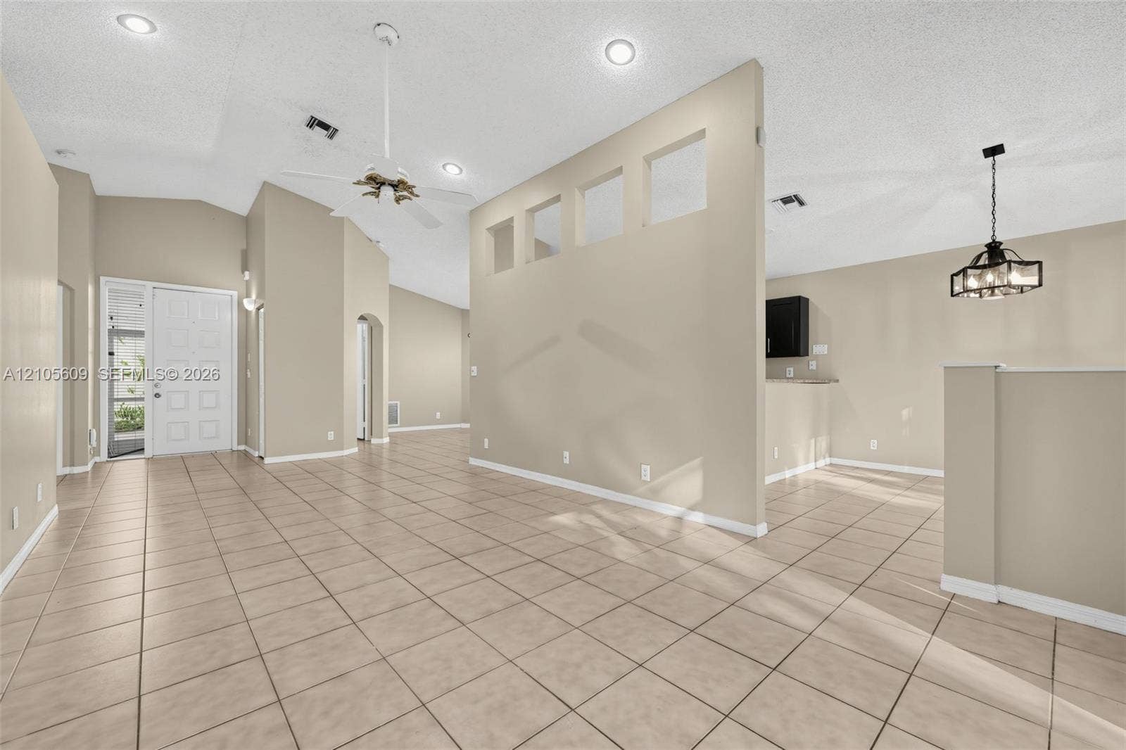 Ceramic tile flooring, vaulted ceilings with recessed lighting, interior partition wall with cutout architectural niches, and a multi-light pendant fixture