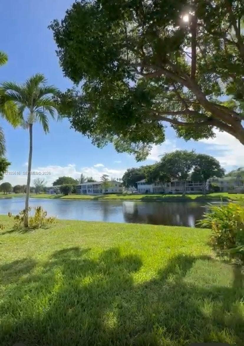 573 Durham U, #573, Deerfield Beach, FL 33442 Waterfront parcel featuring a manicured lawn, mature trees, and palm landscaping