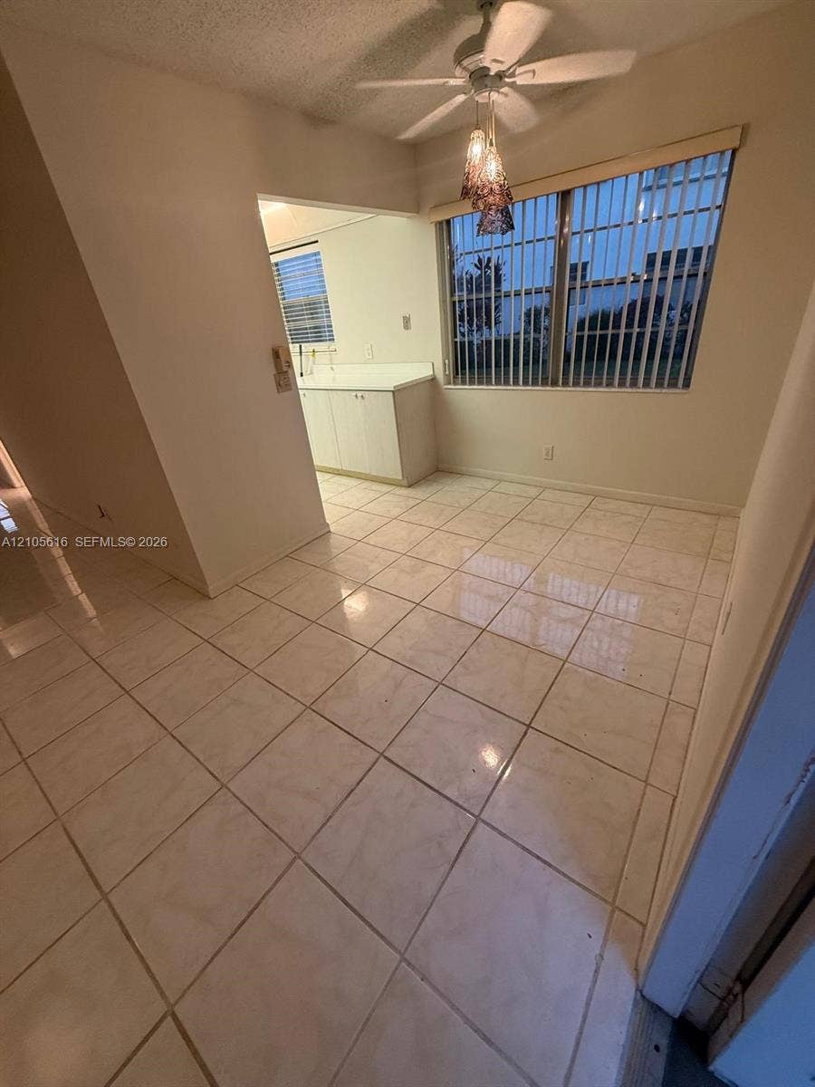 573 Durham U, #573, Deerfield Beach, FL 33442 Ceramic tile flooring, large multi-pane window with vertical blinds, built-in cabinetry with solid-surface countertop, and a multi-light pendant fixture with ceiling fan